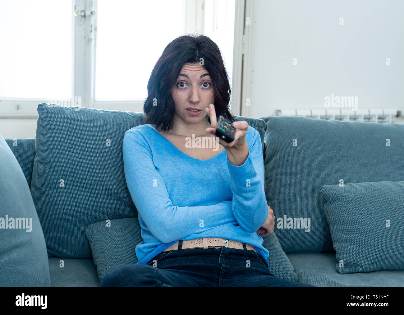 Giovane donna ricalcato sul divano con comando a distanza di zapping annoiato del male di spettacoli TV e la programmazione . Cerca disinteressato, scostante e insonne. Persone, troppo Foto Stock