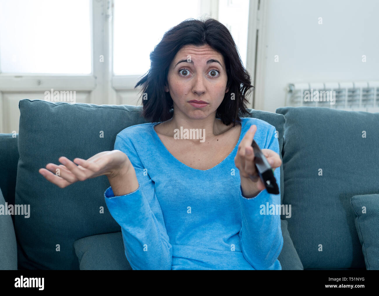 Giovane donna ricalcato sul divano con comando a distanza di zapping annoiato del male di spettacoli TV e la programmazione . Cerca disinteressato, scostante e insonne. Persone, troppo Foto Stock