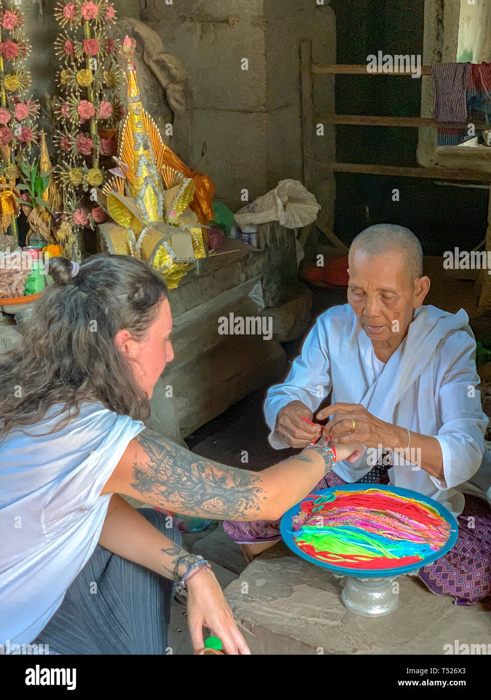 Siem Reap, Cambogia - Marzo 26, 2019 : Turisti ricevere la benedizione da monaca buddista nel tempio di Angkor complesso in Cambogia. Foto Stock