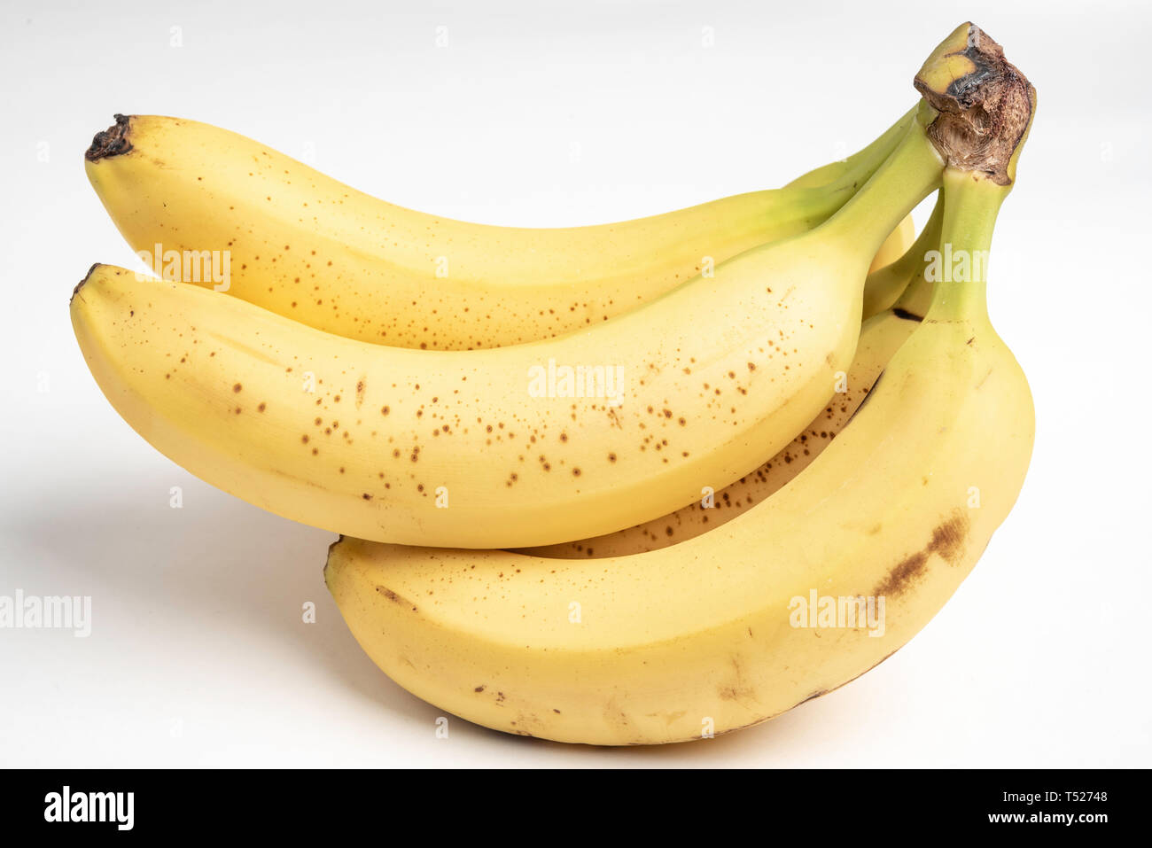 Un primo piano o un macro shot di un mazzo di banane gialle sopramature su uno sfondo bianco chiaro. Foto Stock
