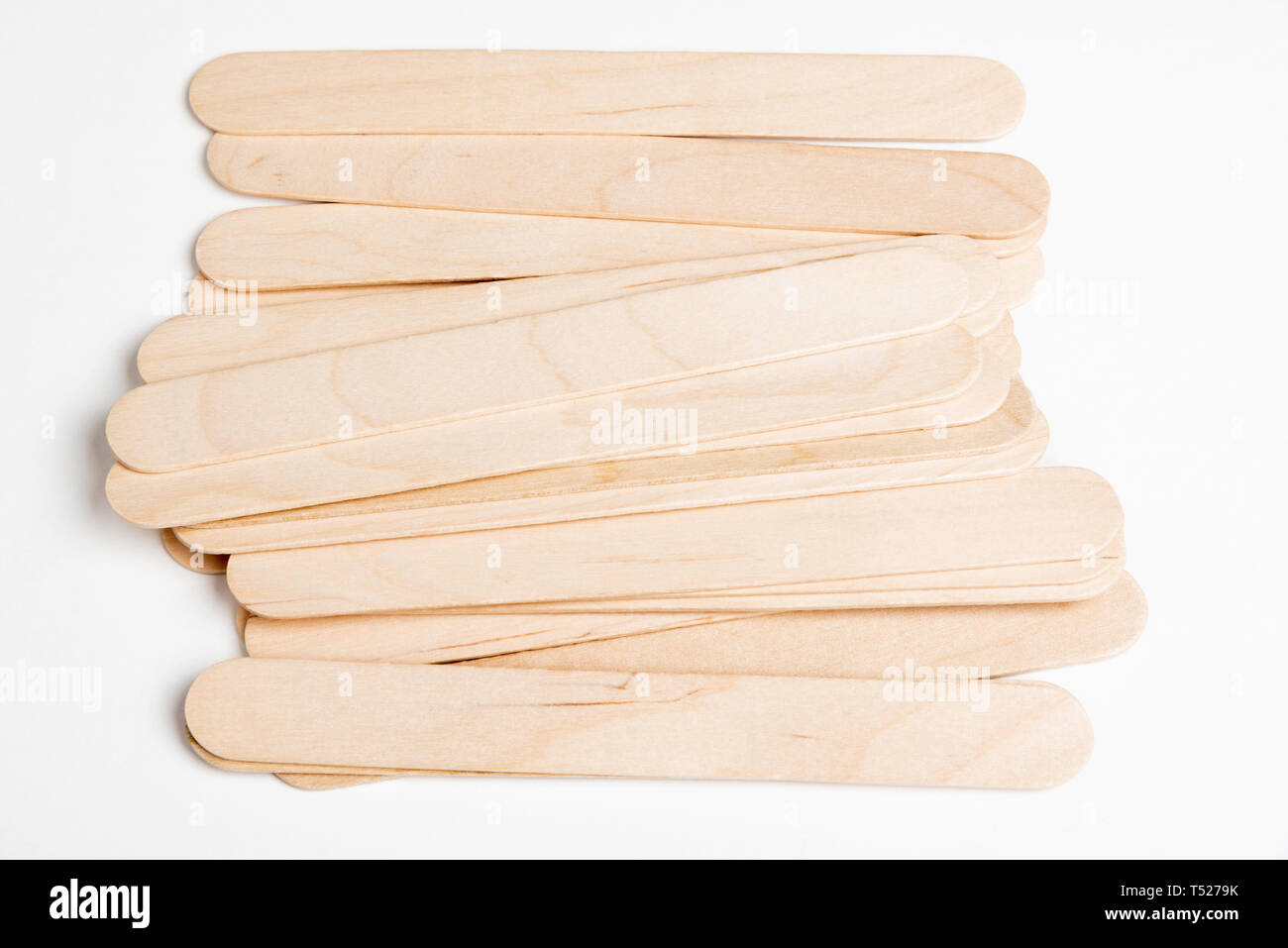 Una pila o una serie di bastoni di artigianato di legno spesso inutilizzati su uno sfondo bianco semplice. Foto Stock