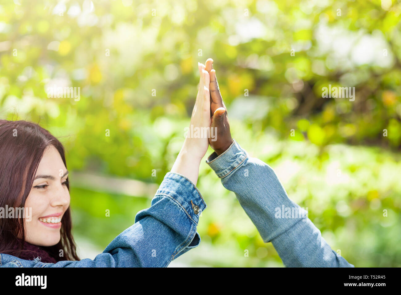 Caucasico bianco e nero americano africano degli studenti tenendo le mani insieme in unità mondiale la razza di amore e di comprensione del concetto. Foto Stock