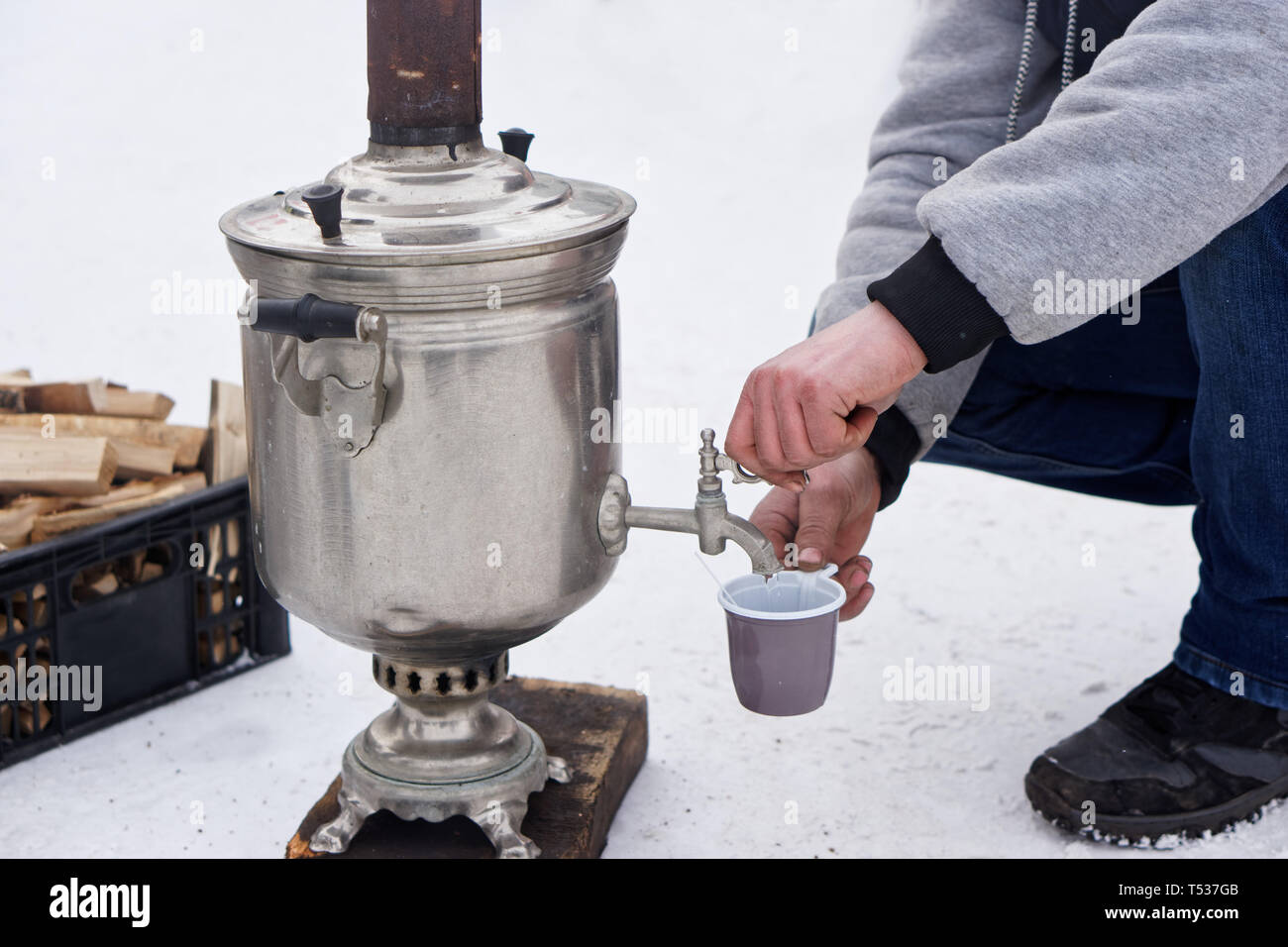 Un uomo si versa acqua bollente da un samovar durante un picnic d'inverno. Tradizioni e passatempo Foto Stock