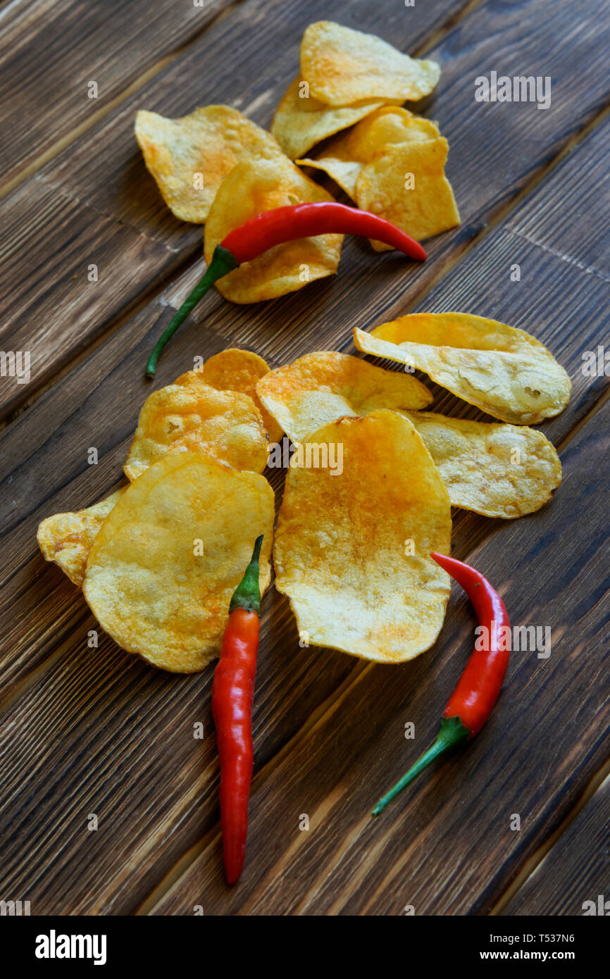 Patate fritte e red hot chili peppers su un rustico in legno tavolo realizzato da tavole di pino. La luce diurna. L'immagine verticale. Foto Stock