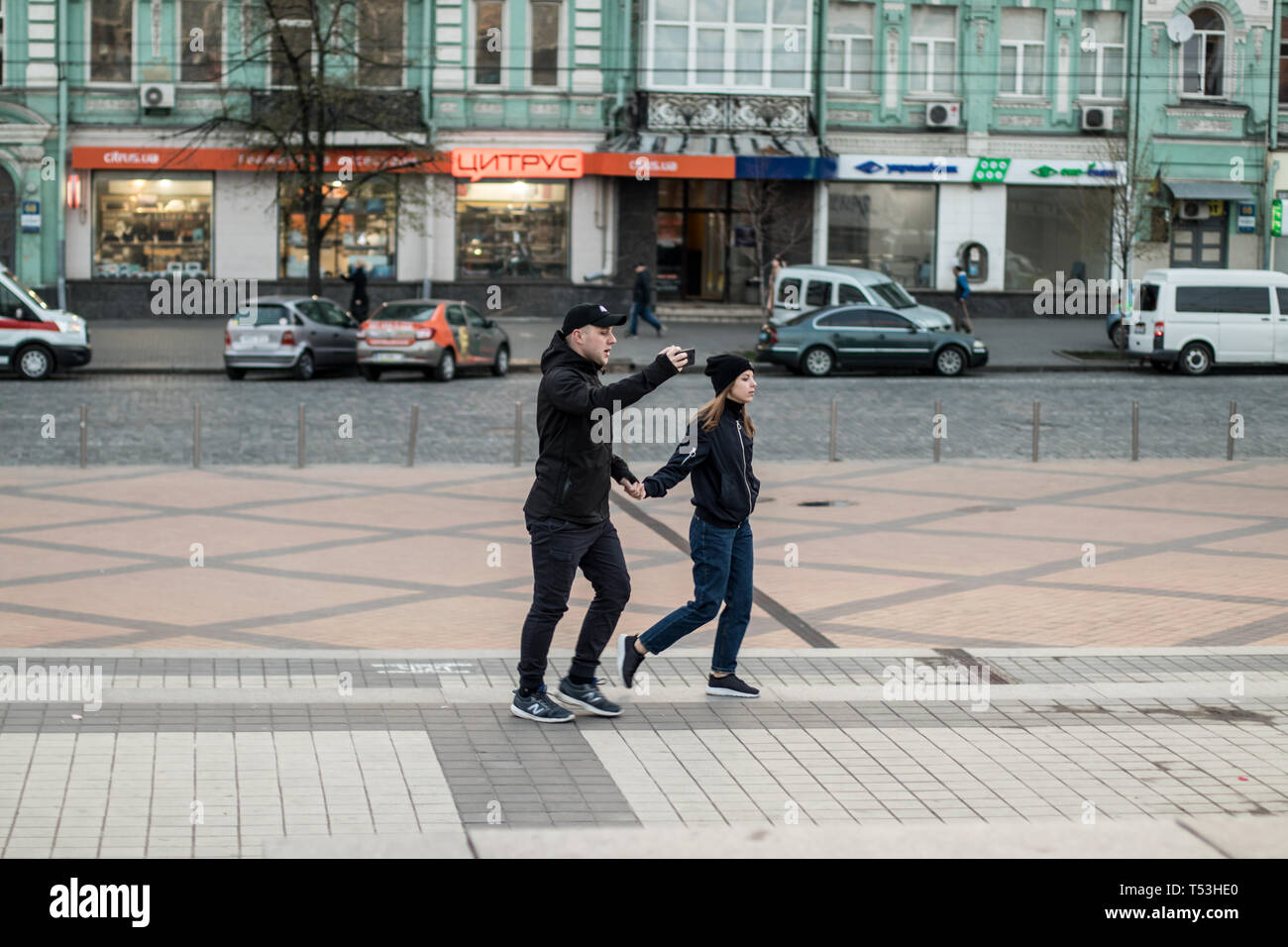 Un giovane guarda live aria mentre camminare vicino a Kyiv Olympiyskiy Stadium al dibattito presidenziale evento. Folla e corpi di polizia in azione. Foto Stock