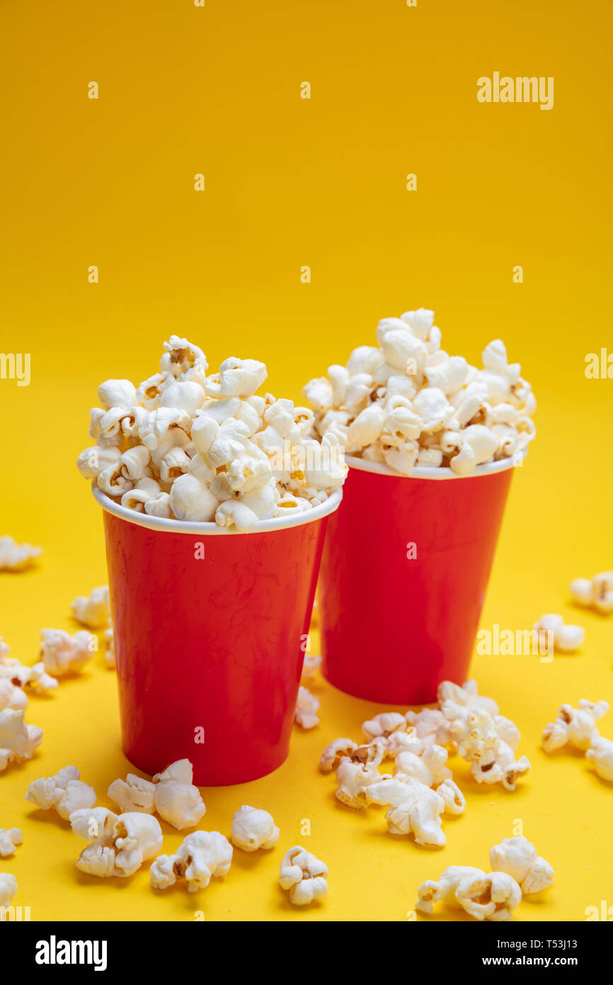 Salate fresche pop corn in rosso due contenitori di cartone, giallo colore di sfondo Foto Stock