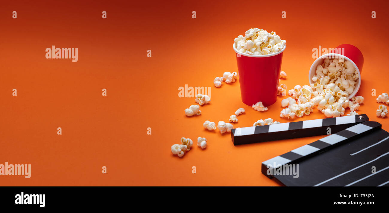 Cinema concetto. Salate fresche pop corn e movie clapper board, orange Colore di sfondo, banner Foto Stock