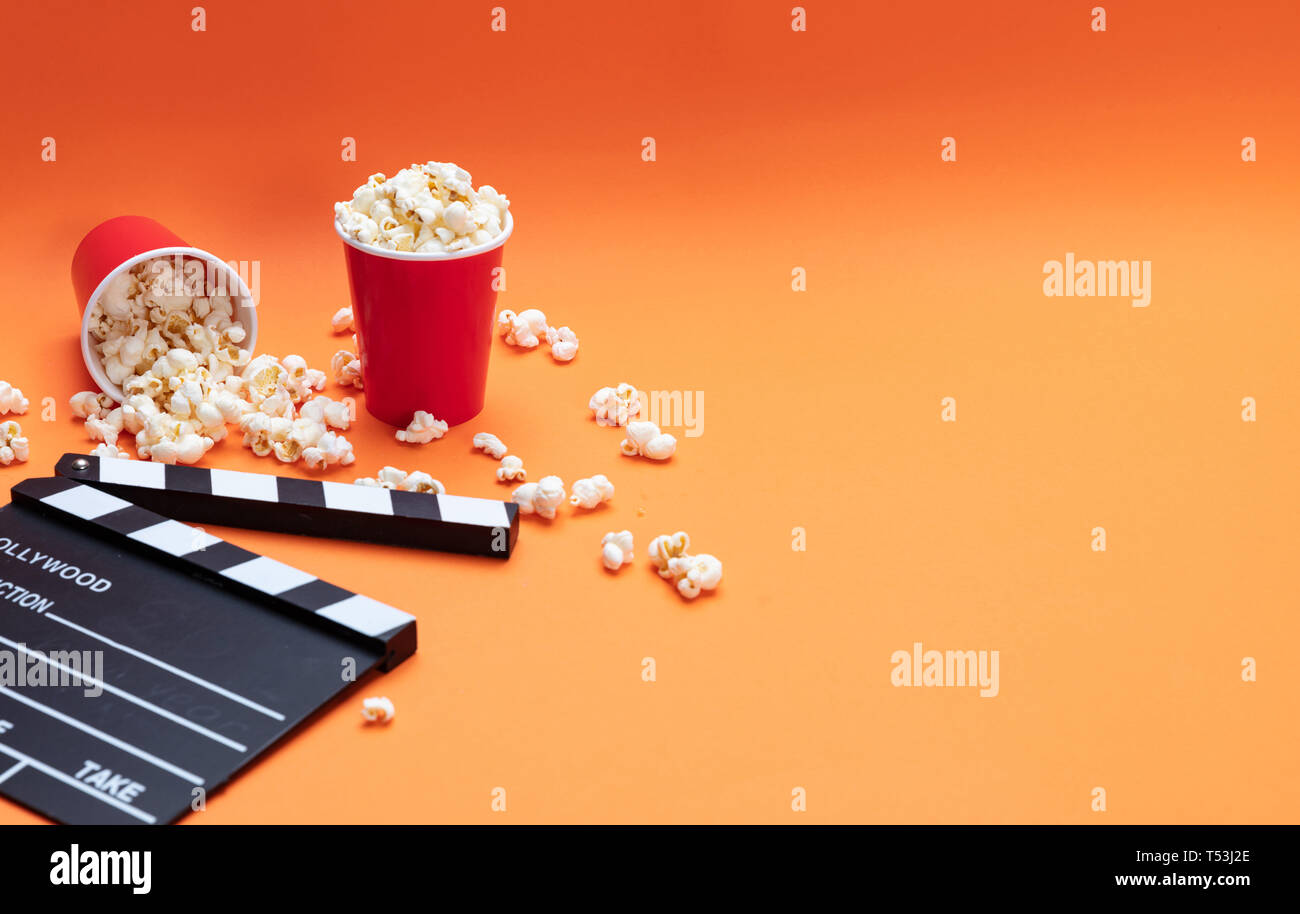 Cinema concetto. Salate fresche pop corn e movie clapper board, orange Colore di sfondo, Foto Stock