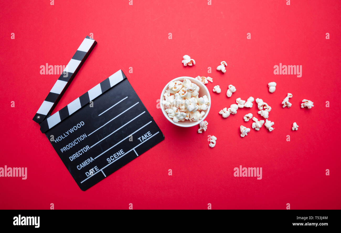 Cinema concetto. Salate fresche pop corn e movie clapper bordo rosso, colore di sfondo, vista dall'alto Foto Stock