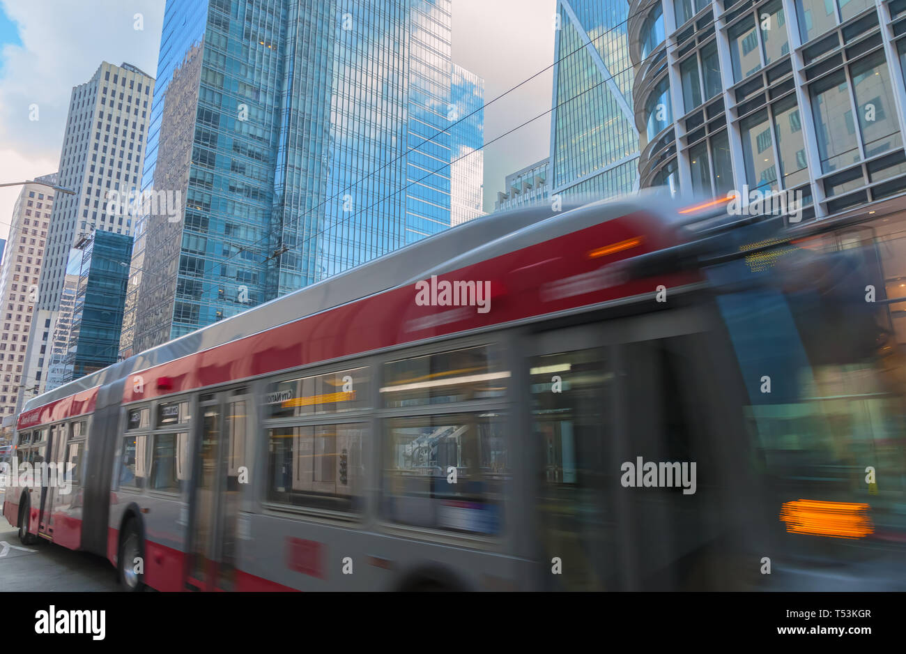 Bus in movimento su strada del centro cittadino di San Francisco, con la città di edifici in background, California, Stati Uniti. Foto Stock