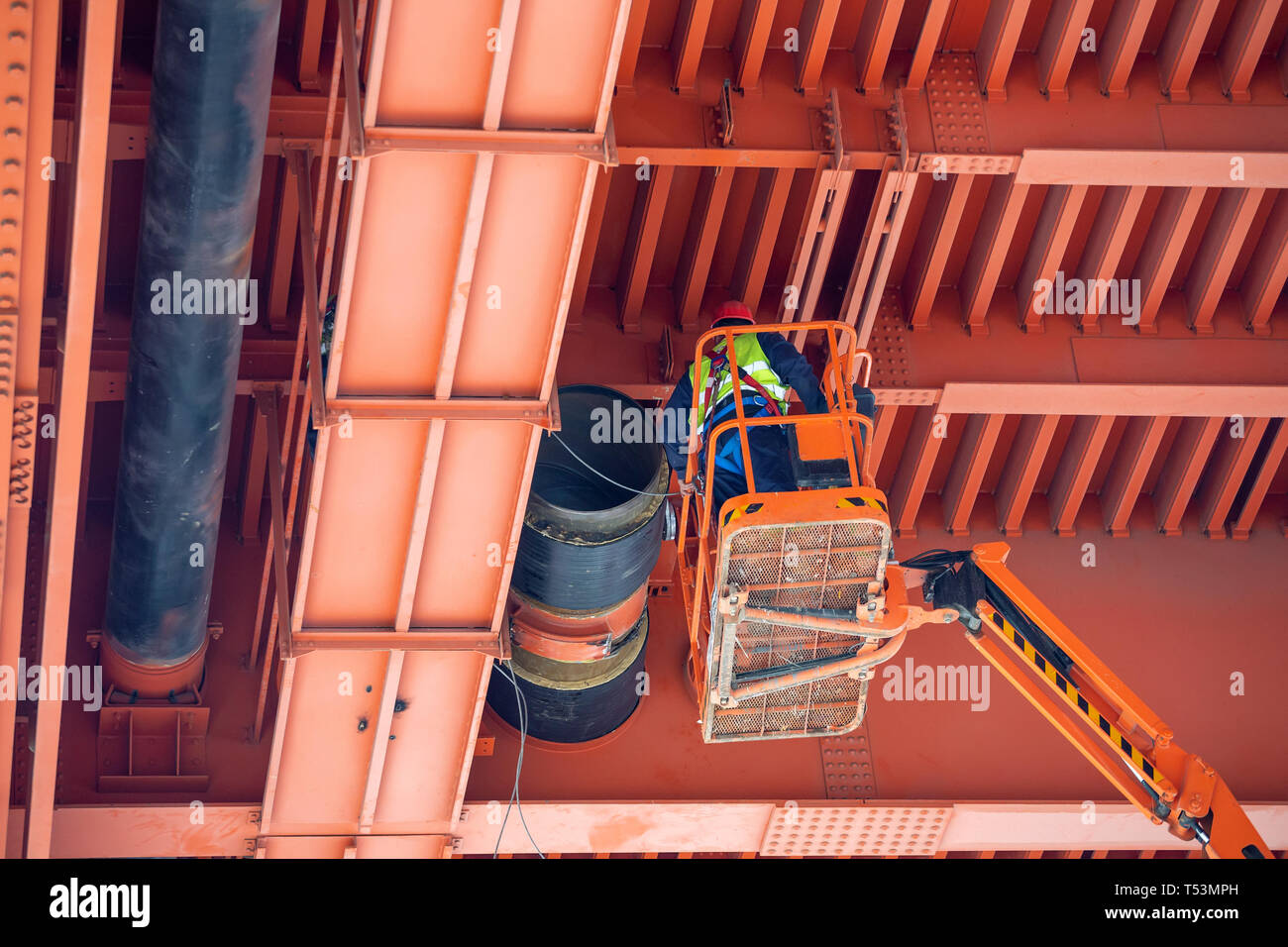 Lavoratori l'installazione di tubi per teleriscaldamento sotto il ponte di metallo. Pipeline di grandi lavori di installazione. Foto Stock