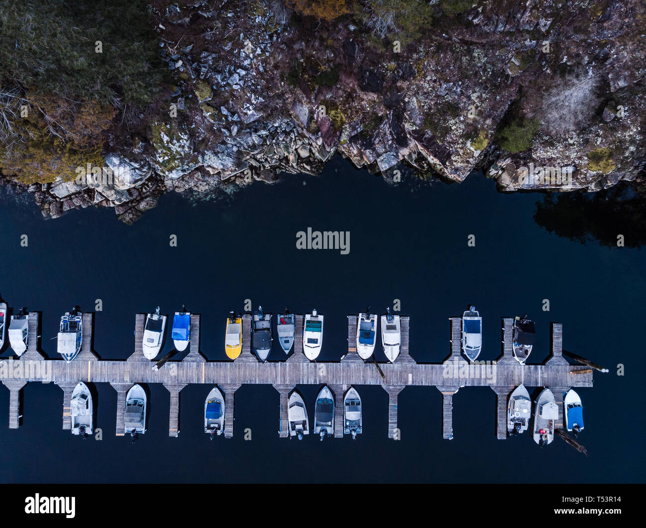 Antenna vista aerea di una imbarcazione in legno dock accanto a una costa rocciosa scogliera Foto Stock