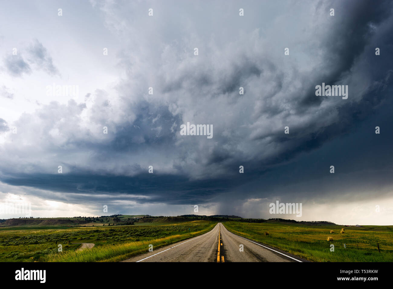 Dritta strada che conduce a scure nuvole temporalesche nei pressi di Joliet, Montana, USA Foto Stock