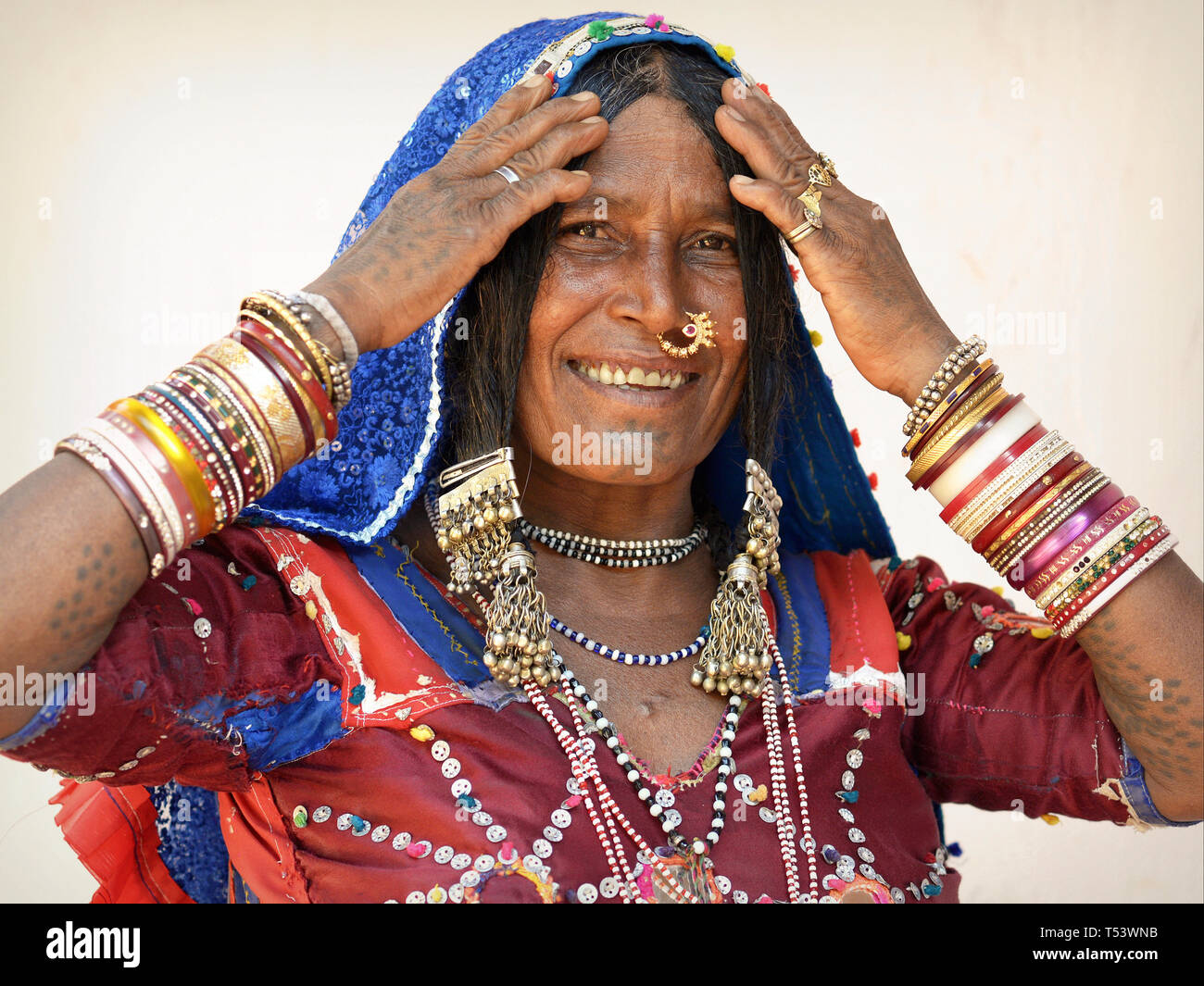 Anziani Lambadi indiano donna (Banjara, Indian gypsy) da Karnataka pone nel suo vestito tradizionale per la telecamera e mostra il suo schiave e gioielli. Foto Stock