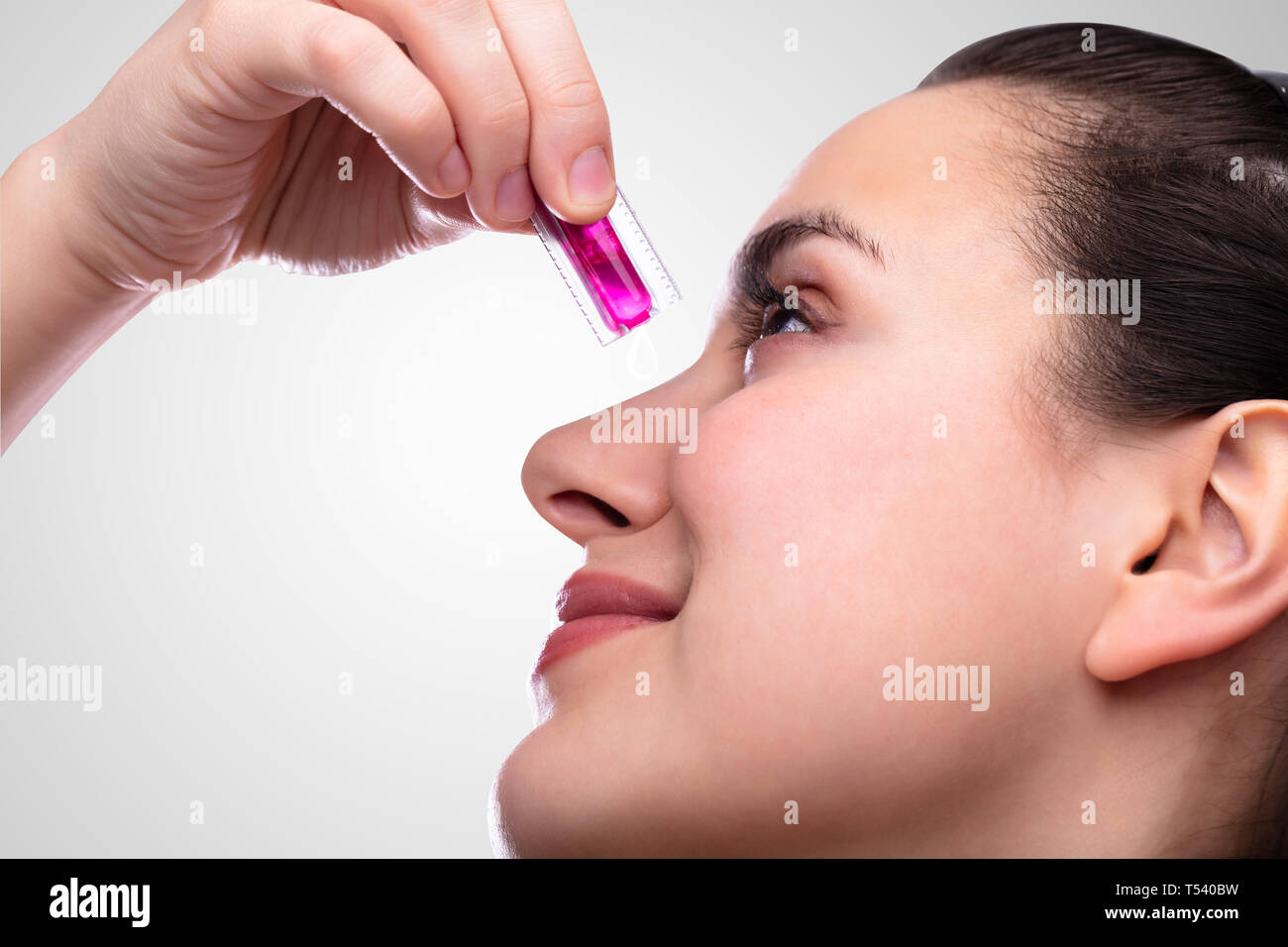 Close-up di giovane donna spremitura a mano vitamina Capsule sul viso Foto Stock