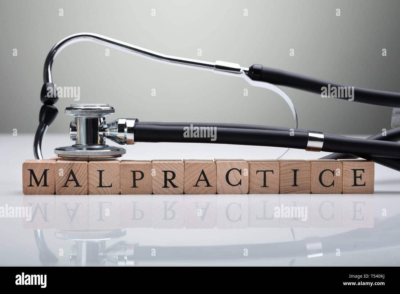 Uno stetoscopio su Irregolarità blocco di legno sulla scrivania bianca davanti a uno sfondo grigio Foto Stock
