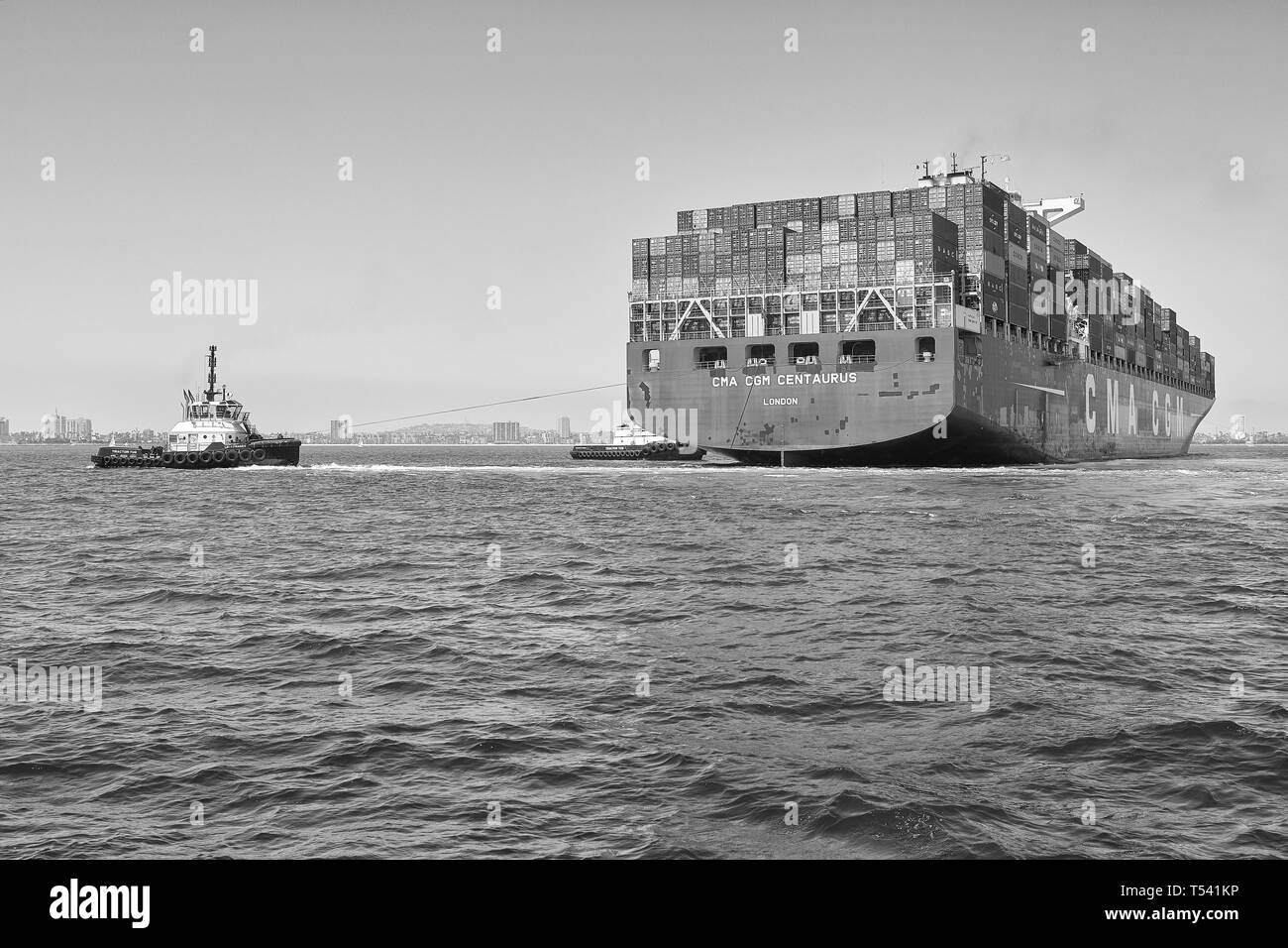 Foto in bianco e nero della nave container, CMA CGM CENTAURUS, girata a 180 gradi da 2 rimorchiatori prima di attraccare a Long Beach, California, USA. Foto Stock