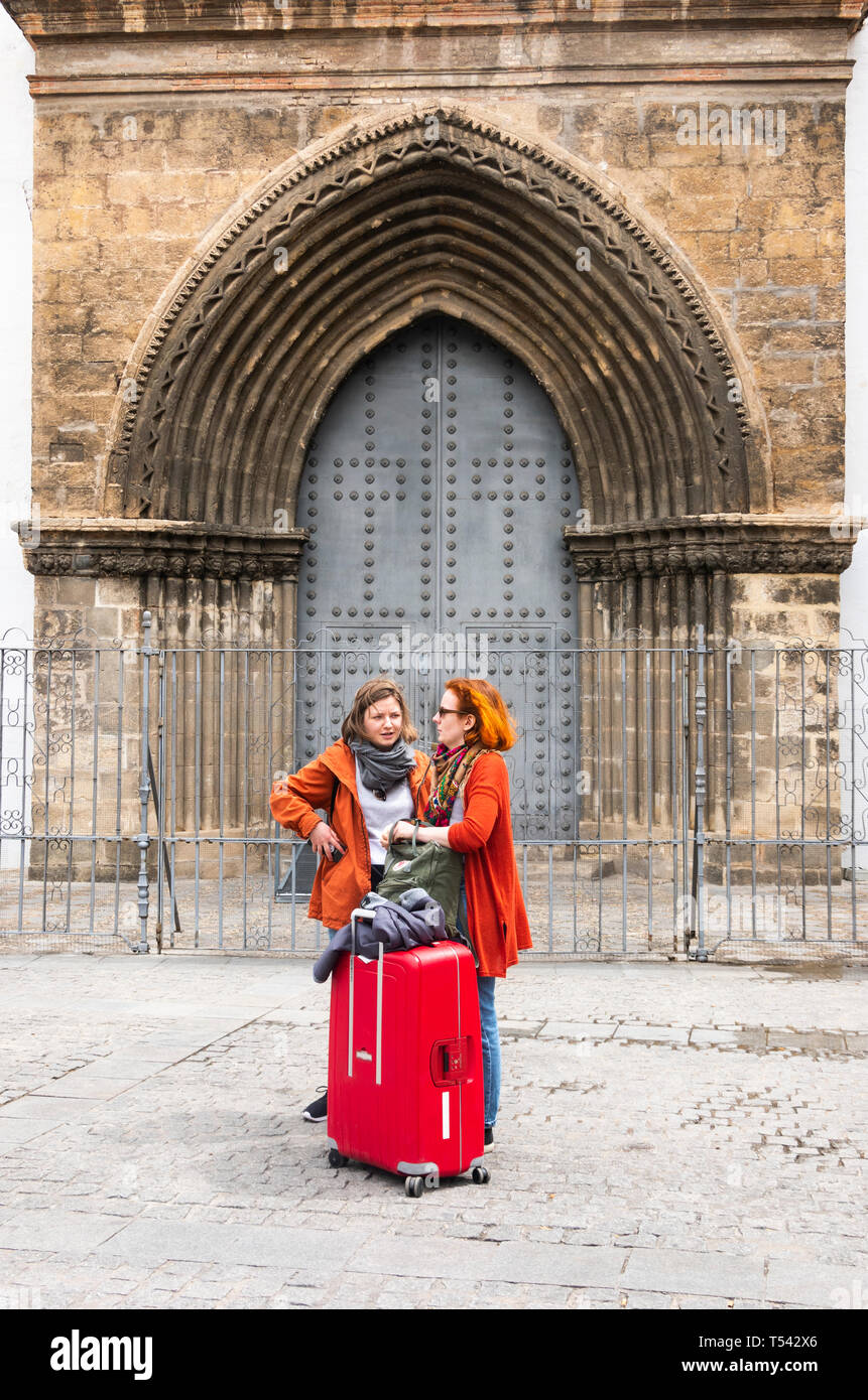 Due donne in attesa di un taxi di fronte ad una chiesa di Siviglia Foto Stock