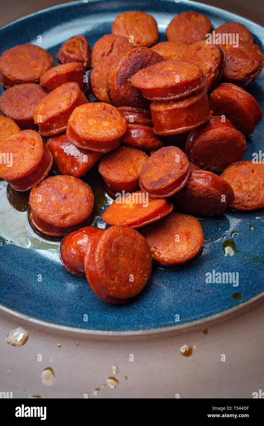 Lo spagnolo cotte tagliate a fette il salame chorizo sul piatto blu Foto Stock