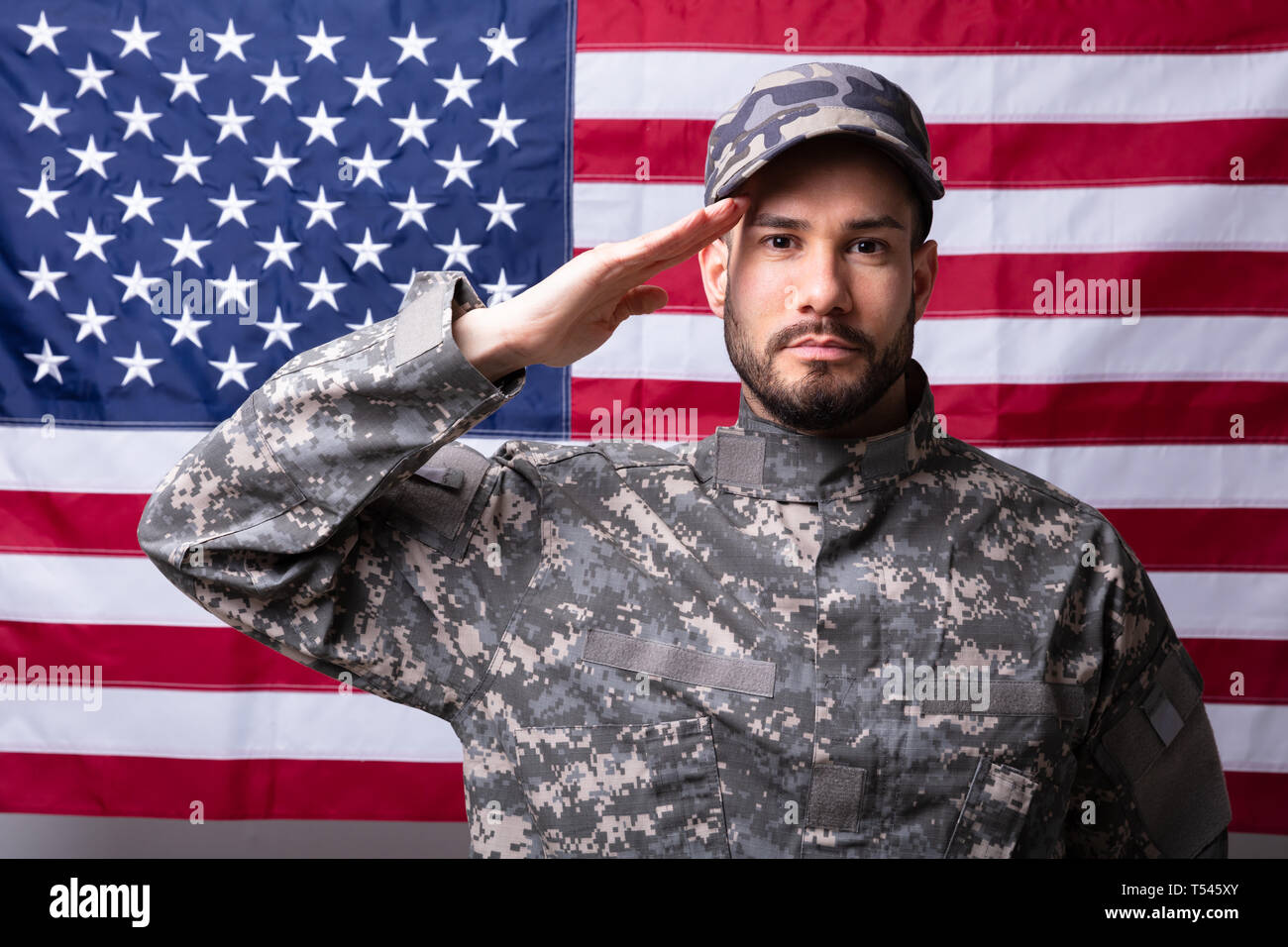 Ritratto di un soldato maschio salutando contro la bandiera americana Foto Stock