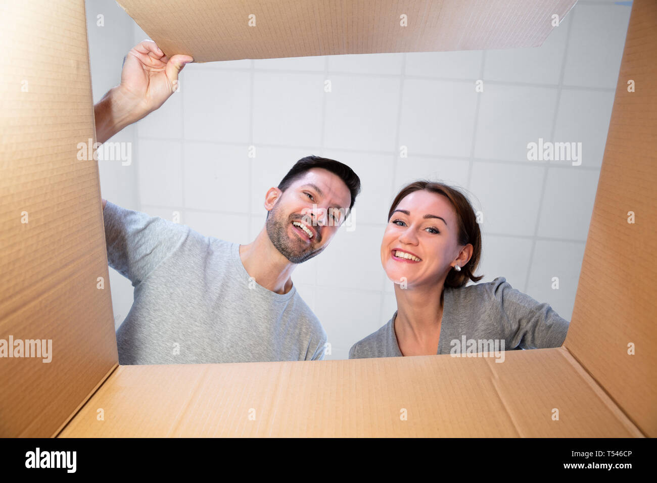 Bassa vista in sezione di una giovane coppia felice guardando all'interno di una scatola di cartone Foto Stock