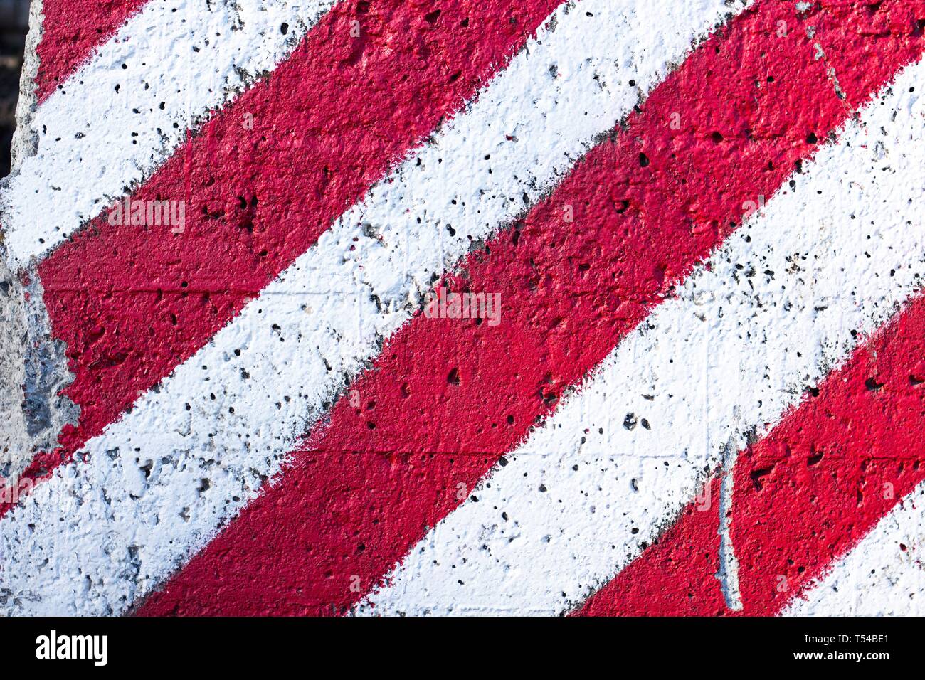 Il bianco e il rosso linee sono disegnate sulla superficie del calcestruzzo. Recinzione di avvertimento sul confine del territorio. Foto Stock