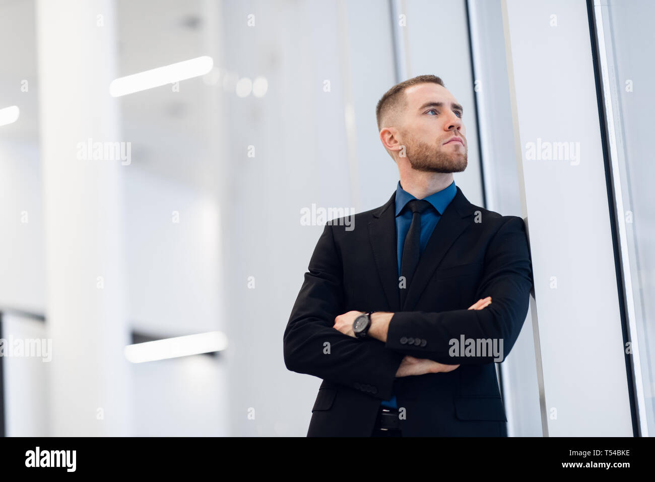 Ritratto di giovane fiducioso elegante uomo d affari con due mani incrociate vicino alla finestra. Foto Stock