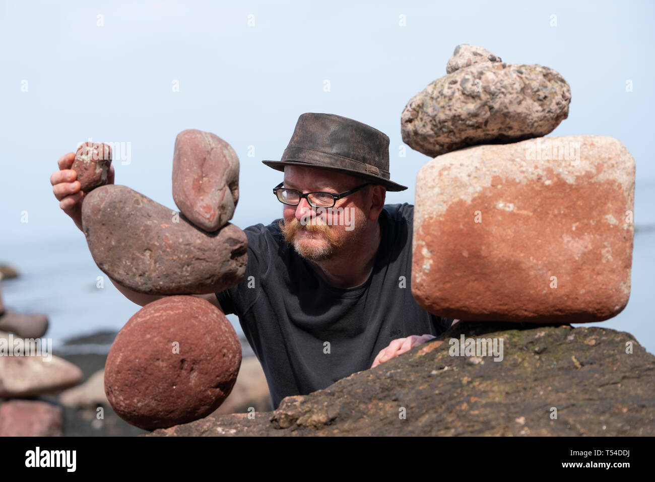 Dunbar, Scotland, Regno Unito. Xx Apr, 2019. Neil Andrews lavorando sulla sua scultura di pietra occhio sulle Cave Beach in Dunbar durante il giorno di apertura del Parlamento di pietra Campionato di impilamento 2019. Credito: Iain Masterton/Alamy Live News Foto Stock