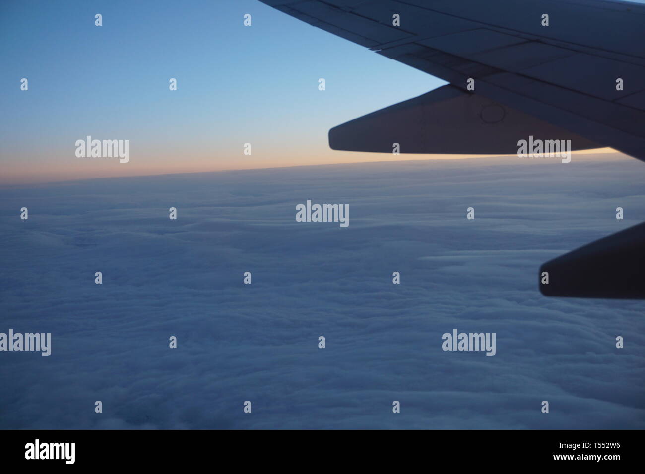 Ala di aeroplano dalla finestra aereo all'alba sopra le nuvole. Foto Stock