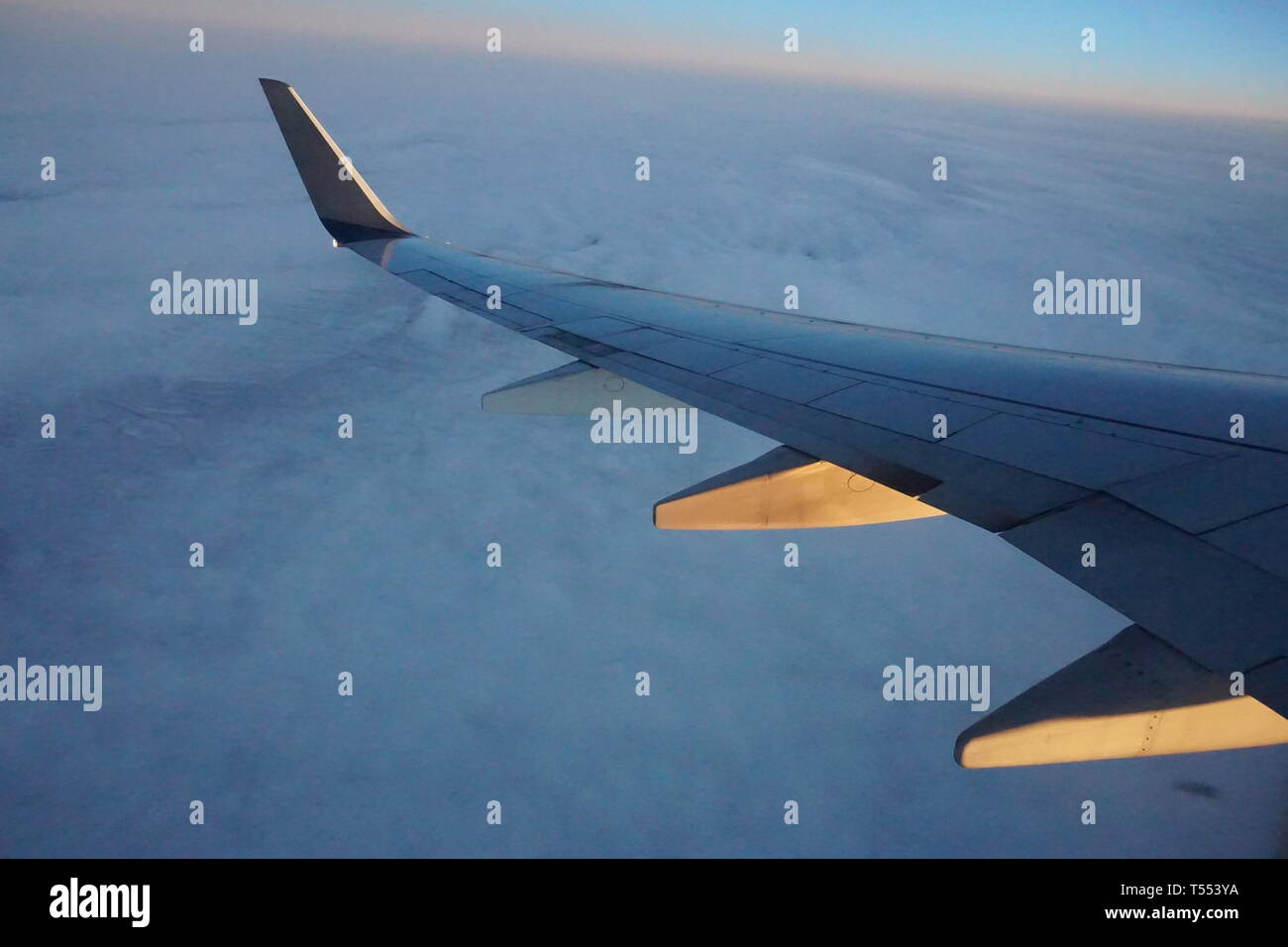 Ala di aeroplano dalla finestra aereo all'alba sopra le nuvole. Foto Stock