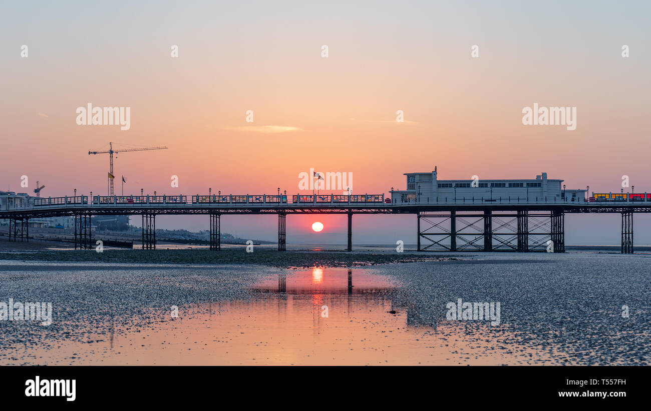 Worthing Sussex, Regno Unito; xx aprile 2019; Dawn con il sorgere del sole dietro a Worthing Pier a bassa marea Foto Stock