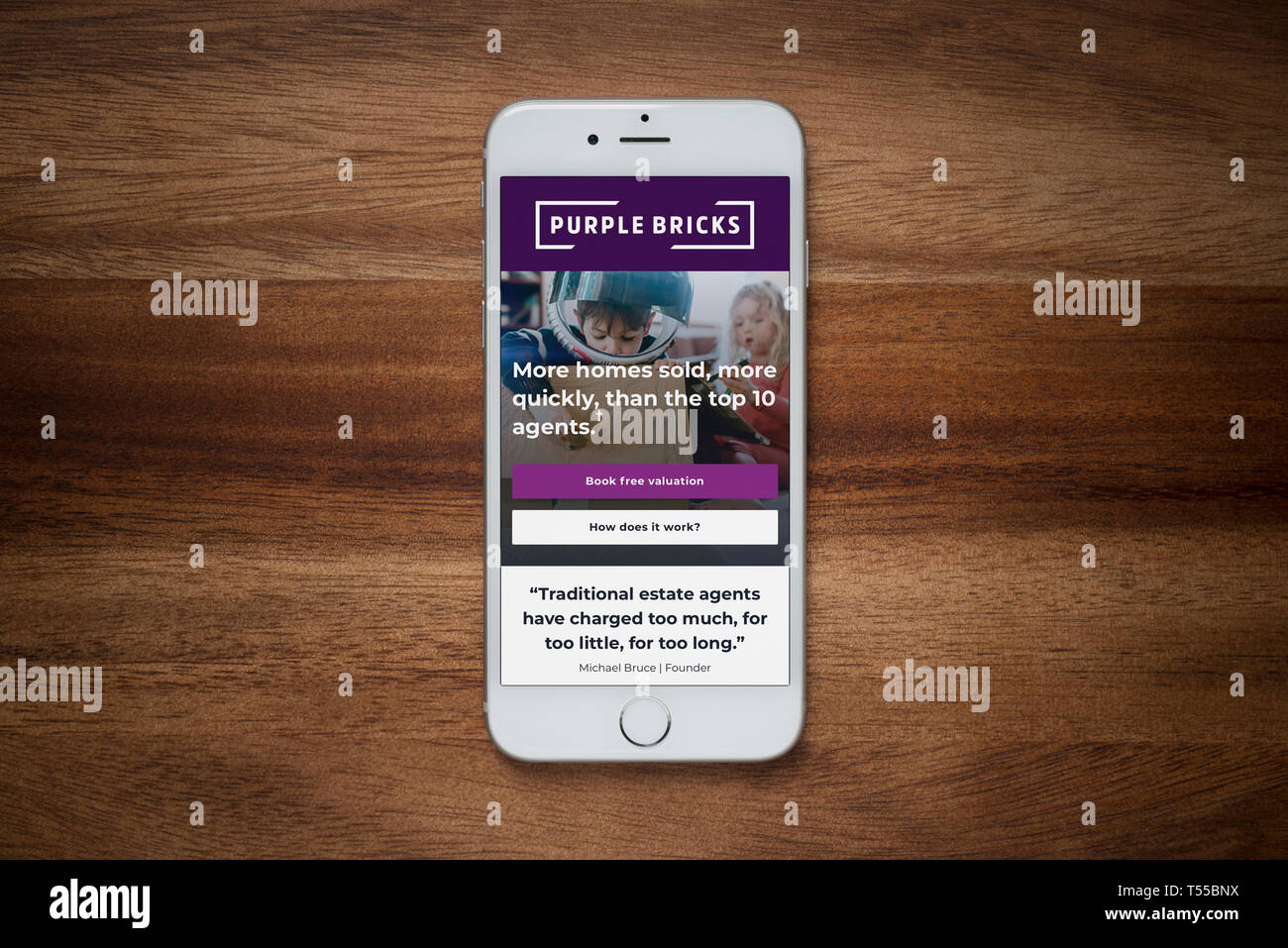Un iPhone che mostra i mattoni viola sito poggia su una semplice tavola di legno (solo uso editoriale). Foto Stock