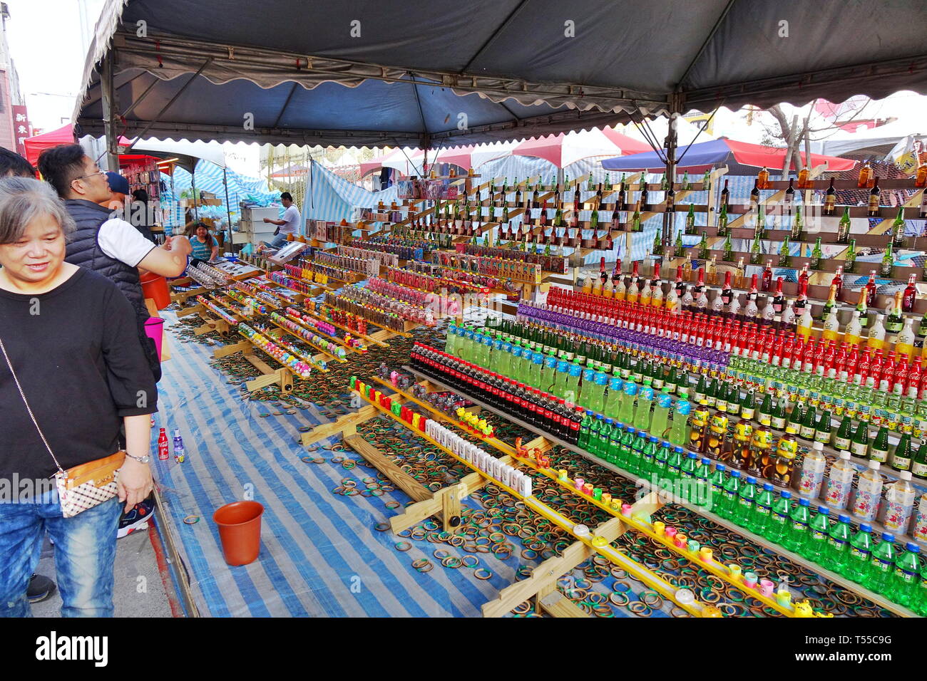 KAOHSIUNG, Taiwan -- Febbraio 6, 2019: persone tenta di gettare gli anelli di bambù al di sopra delle bottiglie in un gioco di abilità a un nuovo anno cinese sul mercato. Foto Stock