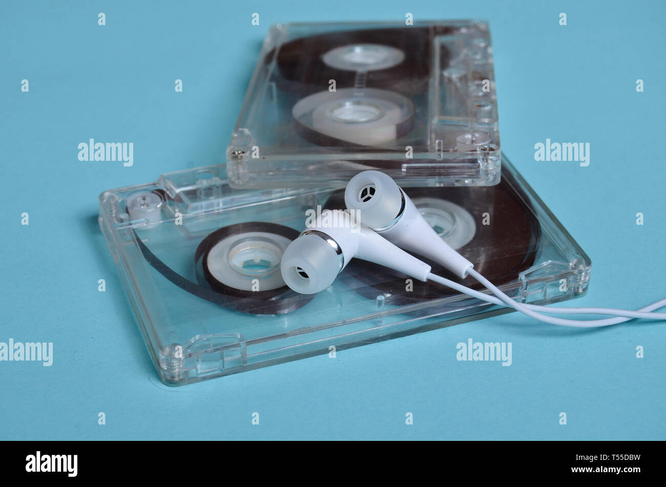 Plastica trasparente cassetta audio e bianco cuffie sotto vuoto su un brillante sfondo blu. 80s. Foto Stock Plastica trasparente cassetta audio e bianco cuffie sotto vuoto su un brillante sfondo blu. 80s. Foto Stock