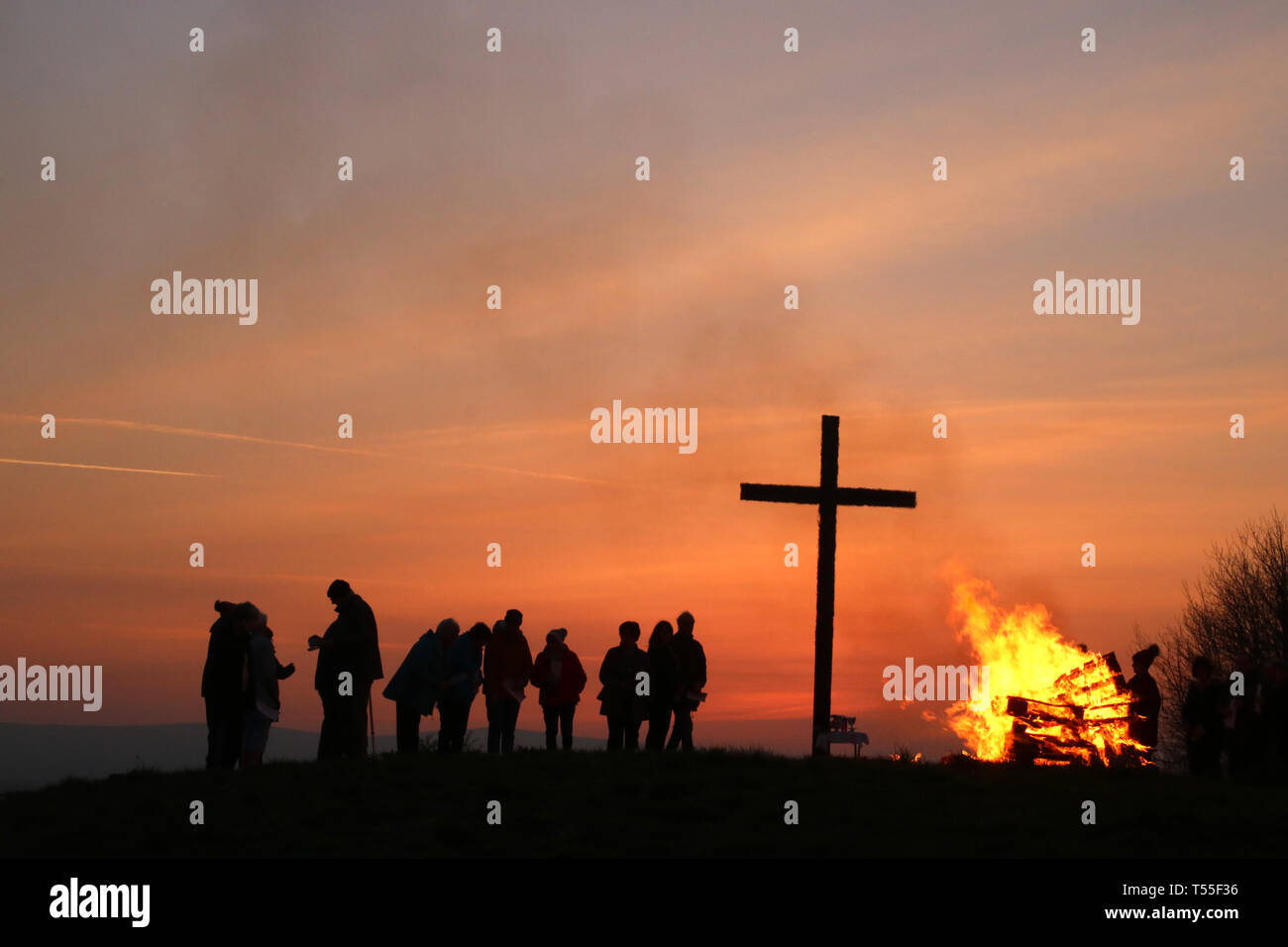 Alba la comunione, il giorno di Pasqua sul mare parete nella formazione di pallini, Preston, Lancashire dalla croce che viene eretta lì ogni anno con sagome di sunrise. Foto Stock