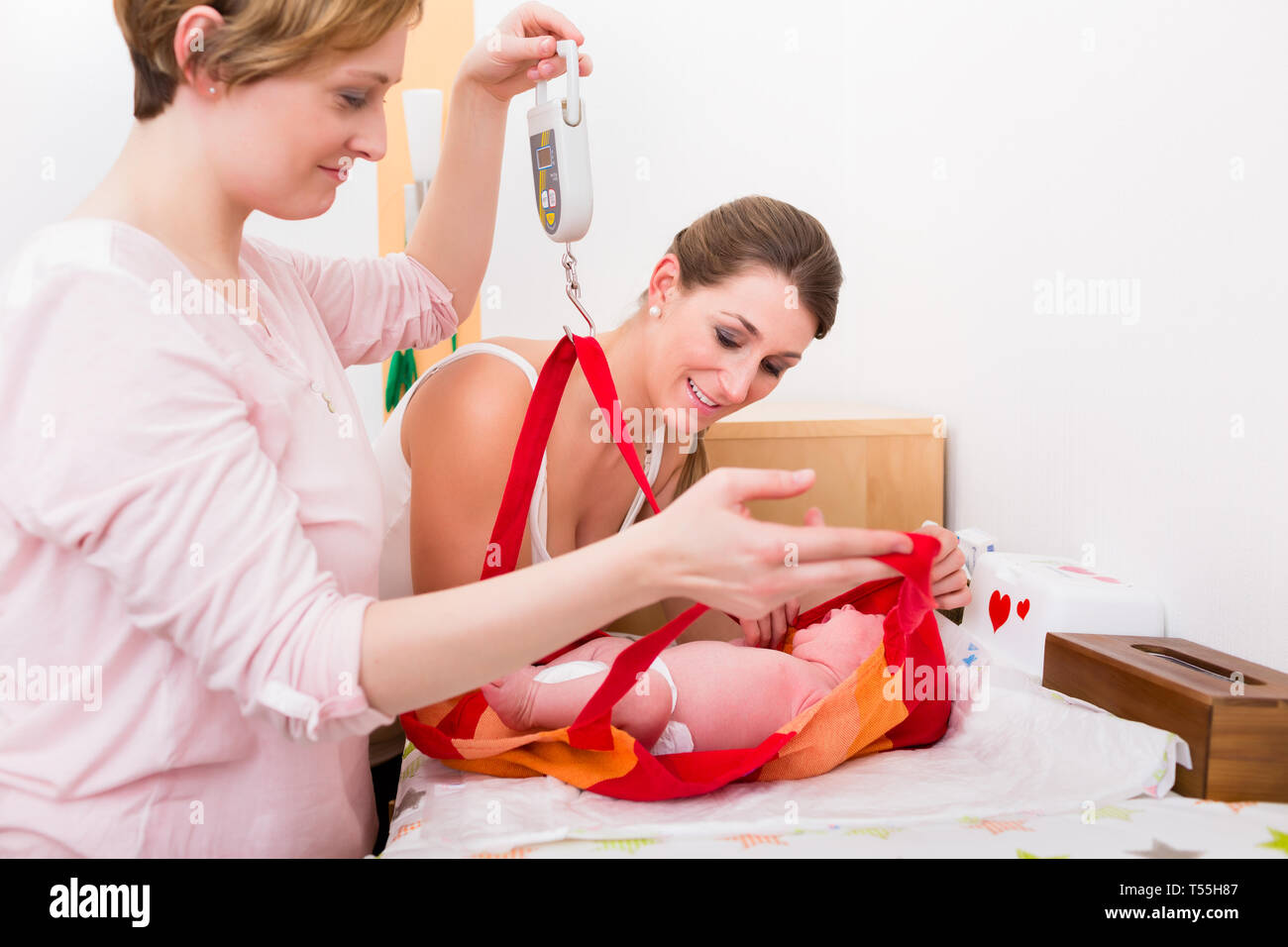 Donne in cerca di baby nella sacca di pesatura Foto Stock