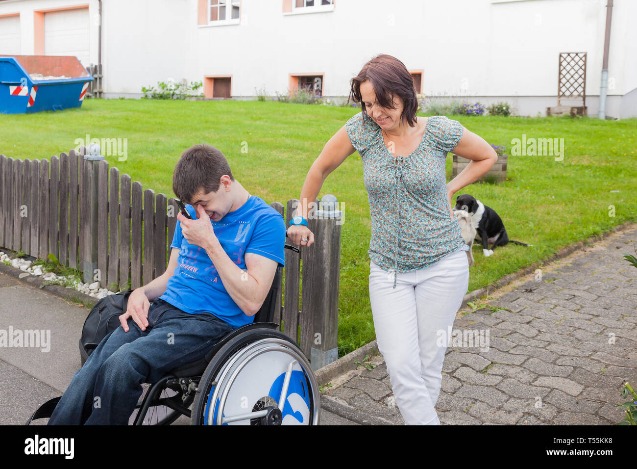 Madre e figlio disabile in attesa per il bus di scuola Foto Stock