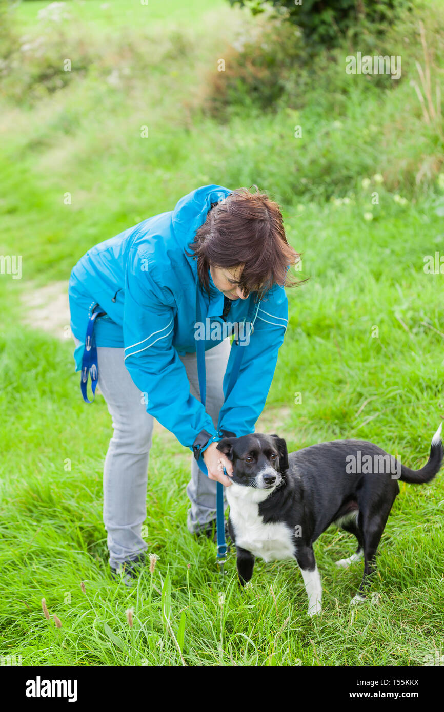 Una donna sta facendo il guinzaglio il suo cane Foto Stock