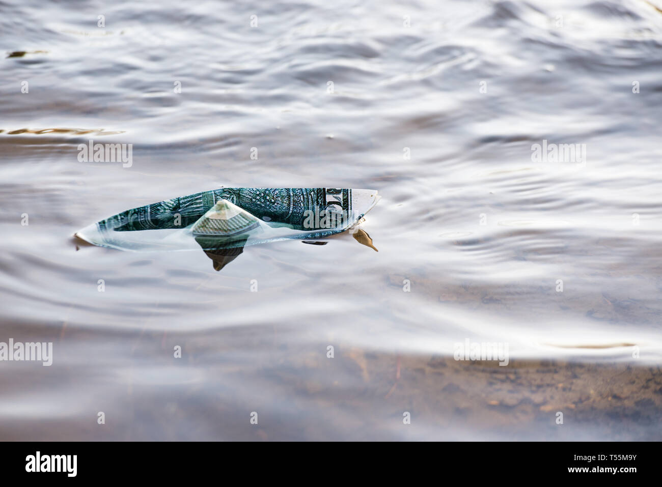 Una barca di carta da un dollaro è in pericolo. Il dollaro è che affonda nell'acqua. Immagine simbolica. Foto Stock