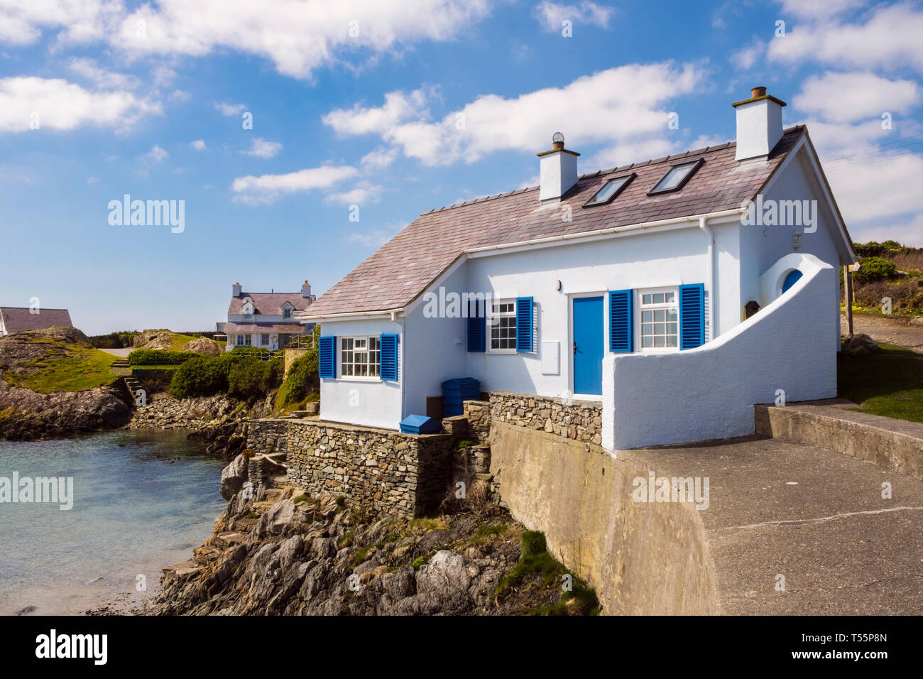 Welsh tradizionali bianco e blu cottage che si affaccia su una insenatura rocciosa nel villaggio costiero. Rhoscolyn, Isola Santa, Isola di Anglesey, Galles del Nord, Regno Unito, Gran Bretagna Foto Stock