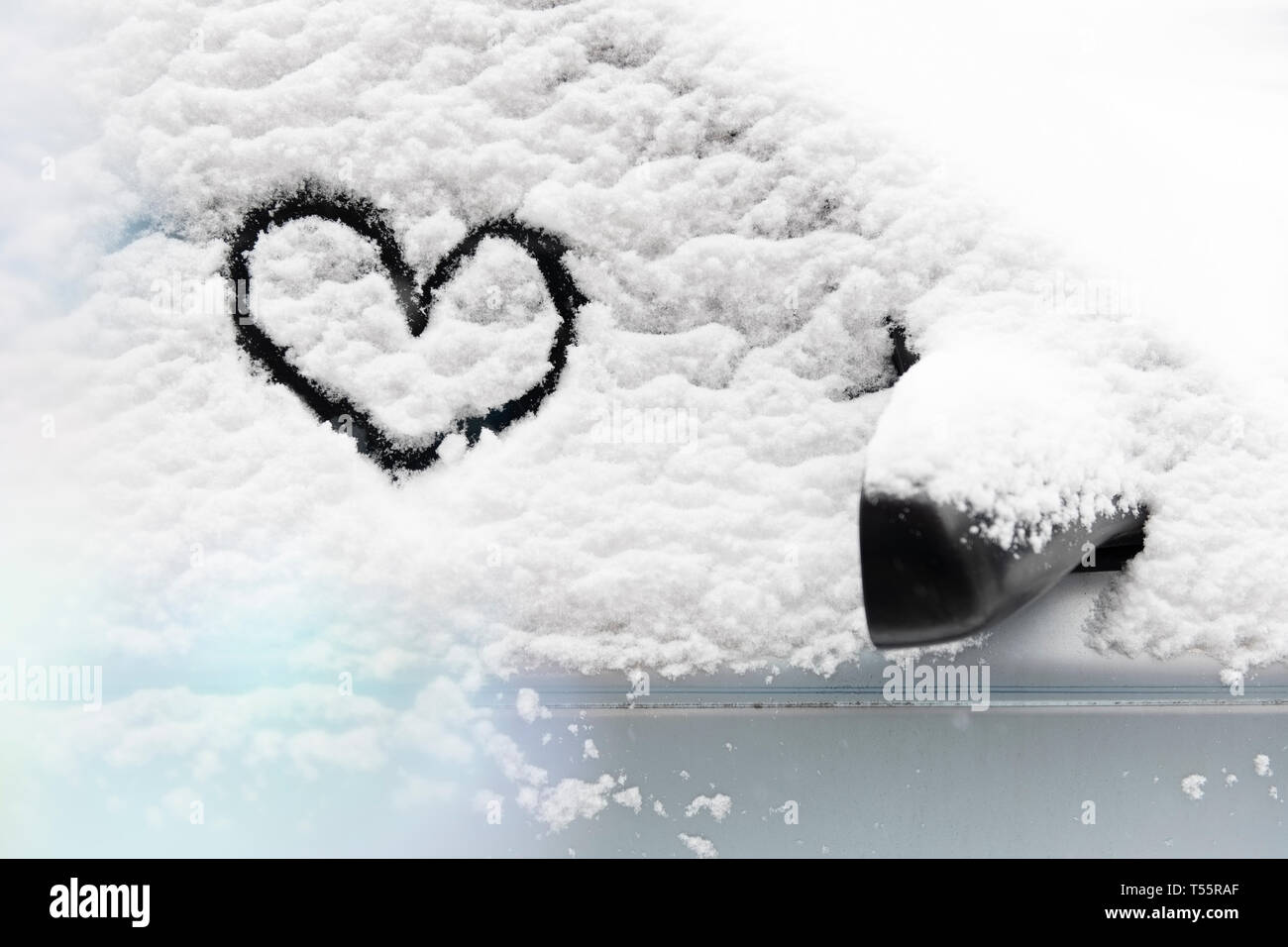 Cuore disegnato in presenza di neve sul vetro per auto Foto Stock