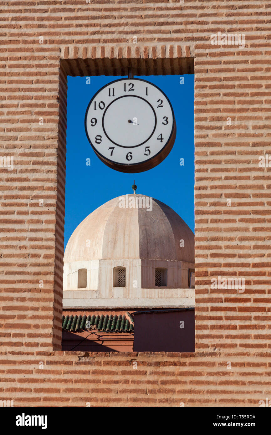 Cupola di mattoni dietro la finestra con orologio in Marrakech, Marocco Foto Stock