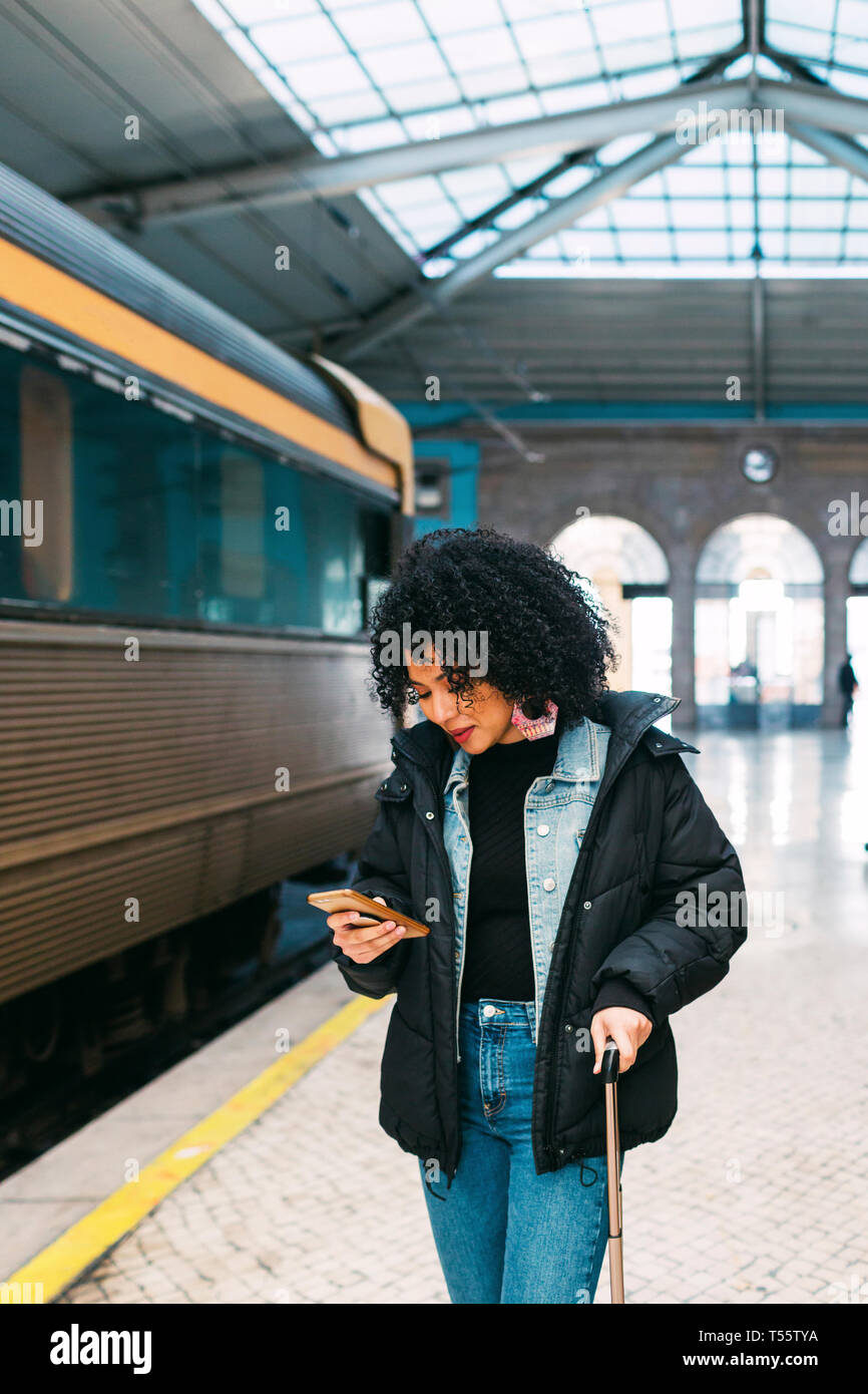 Giovane donna utilizzando smart phone in stazione ferroviaria Foto Stock