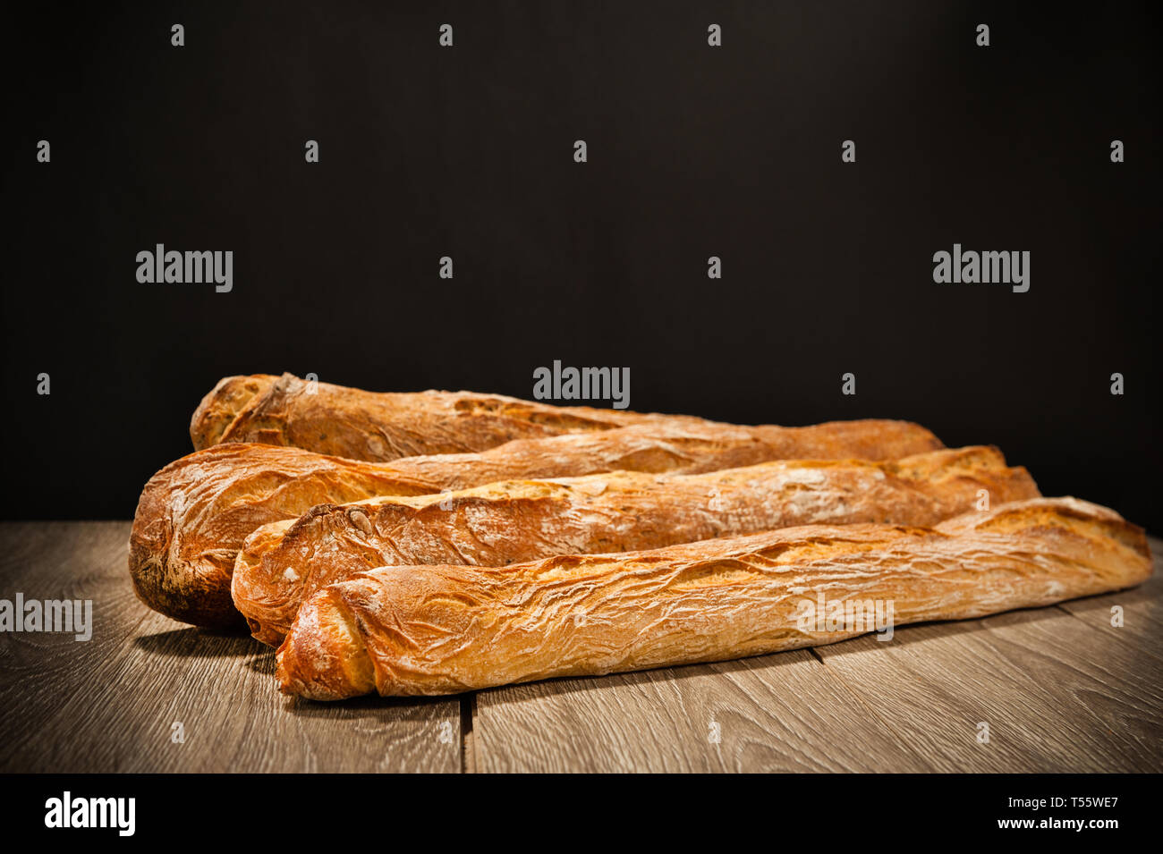 Baguette su una tabella su sfondo scuro Foto Stock