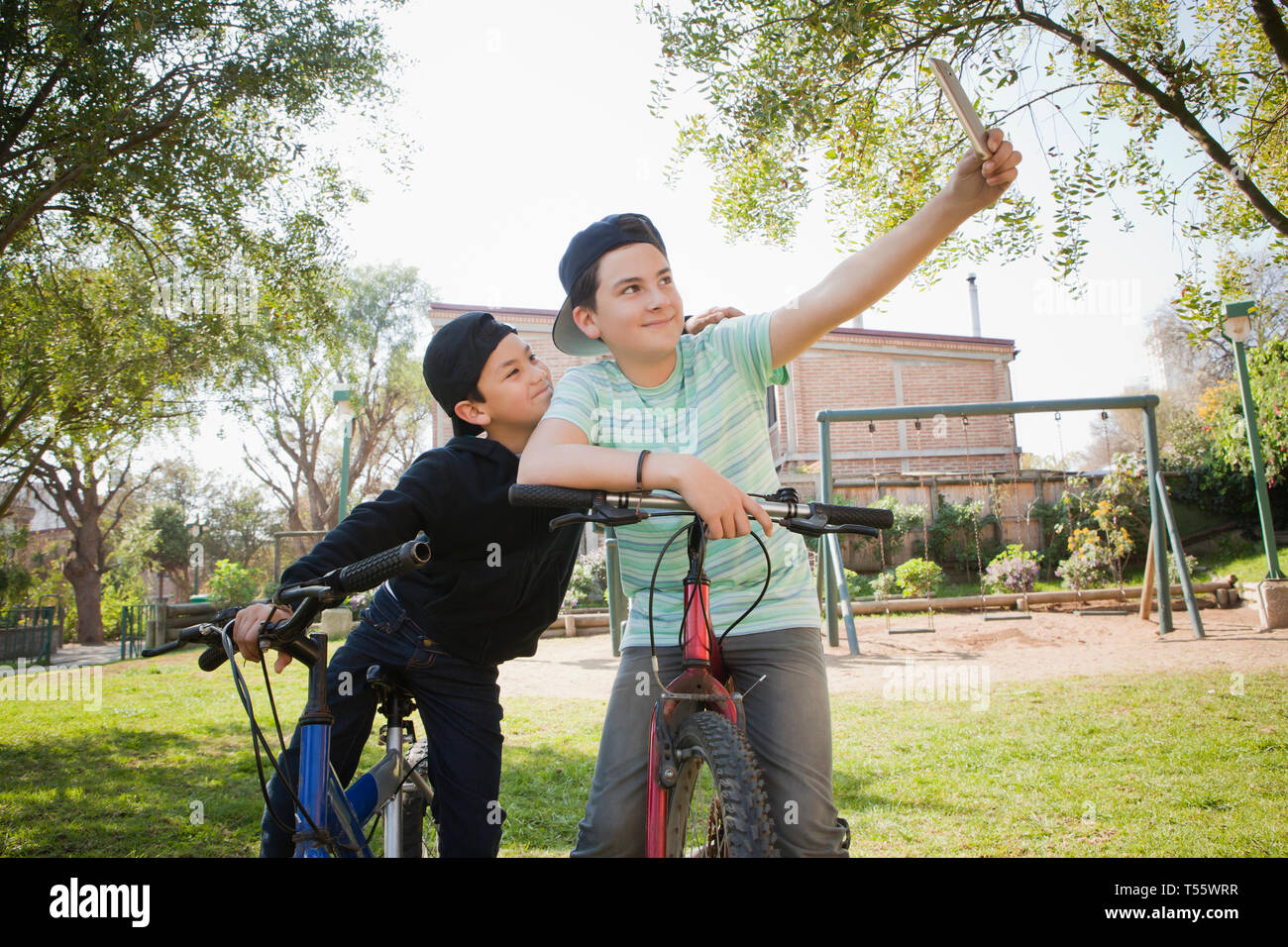 Fratelli tenendo selfie su biciclette Foto Stock