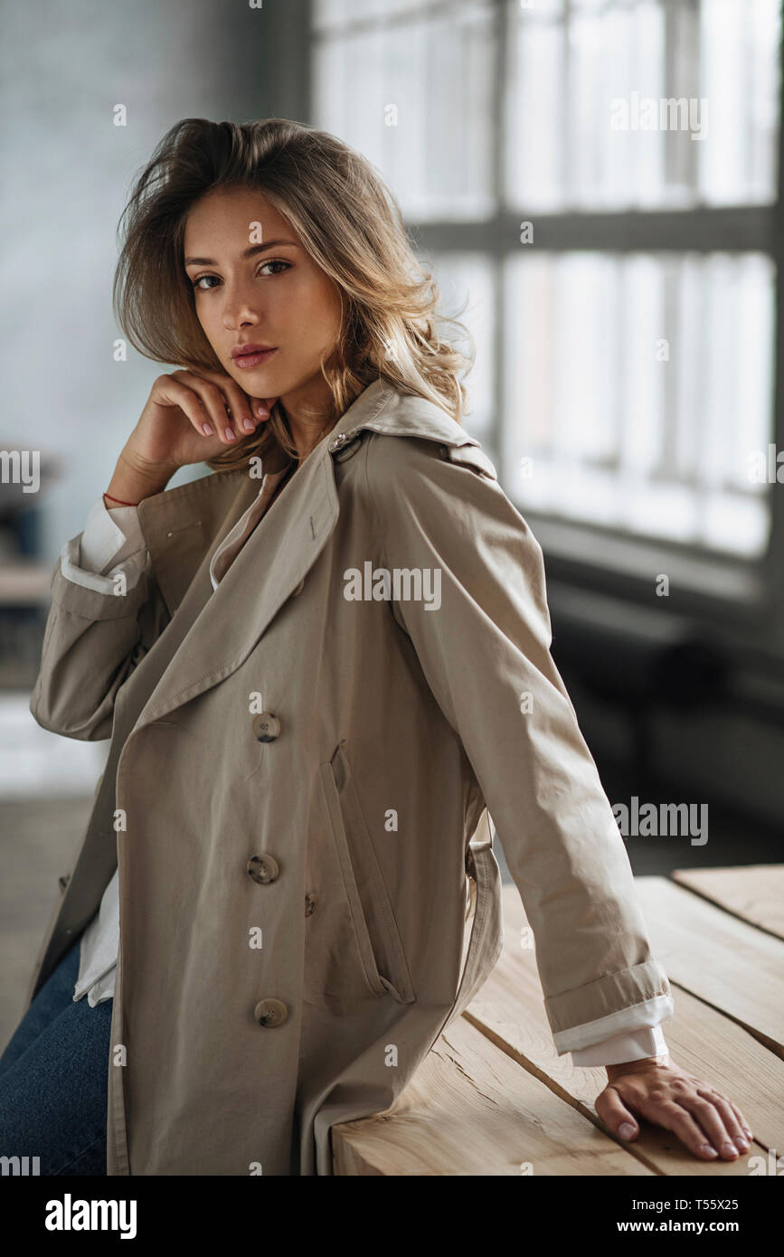 Giovane donna indossa grigio trench coat Foto stock - Alamy