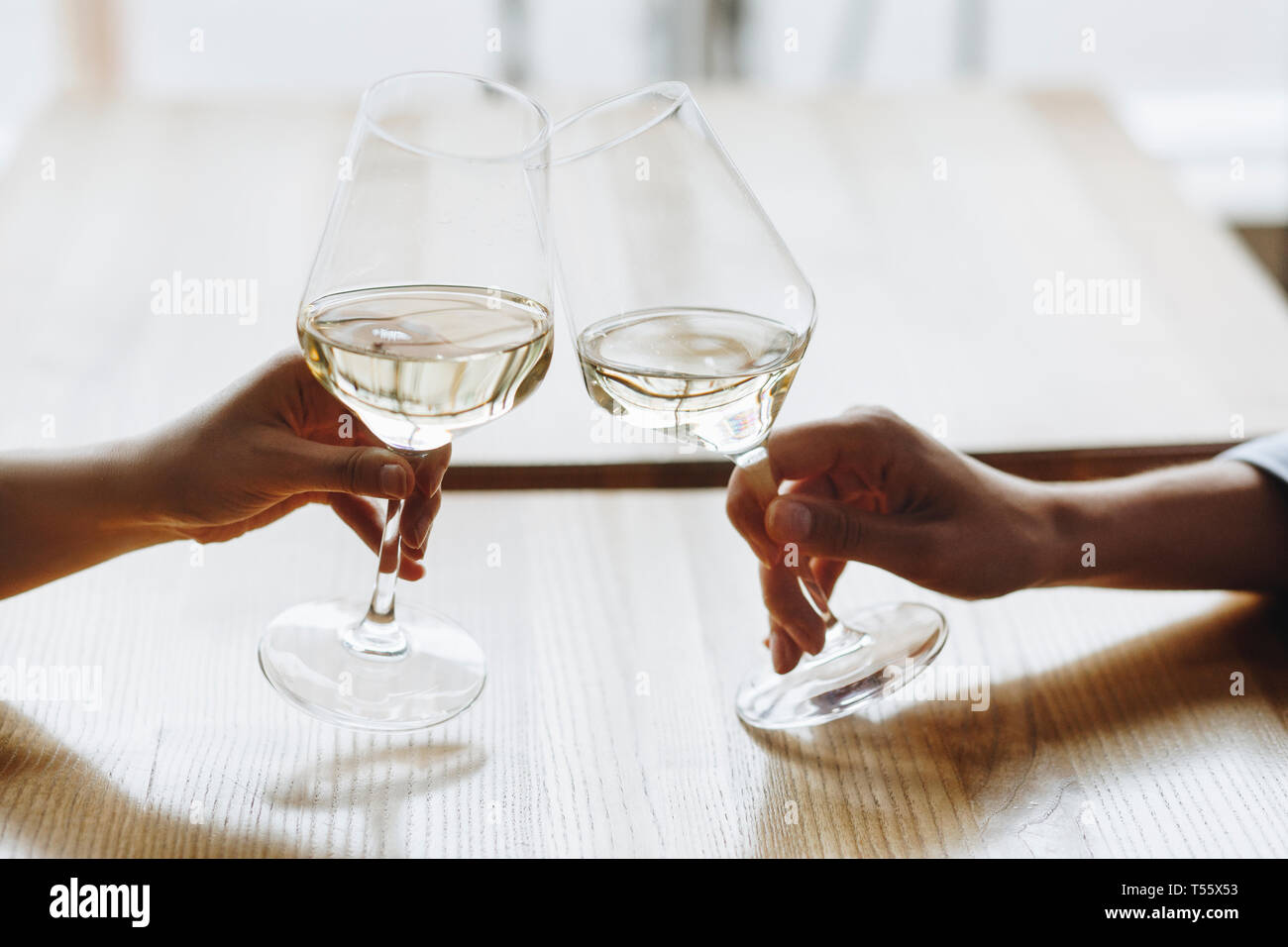 Le mani delle donne la tostatura con bicchieri di vino bianco Foto Stock