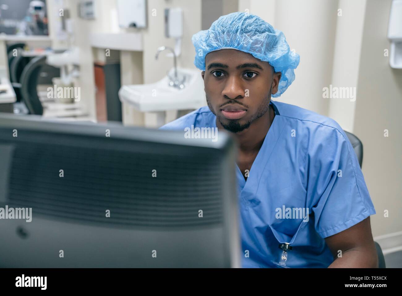 L'infermiera indossando retina per capelli utilizzando computer in ospedale Foto Stock