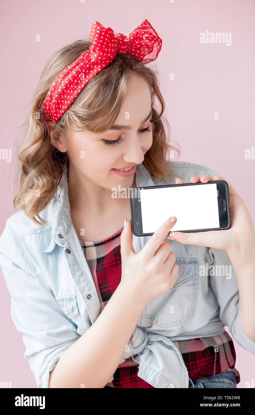 Bella giovane donna con pin-up make-up e acconciatura su sfondo rosa con  telefono cellulare con copia spazio Foto stock - Alamy