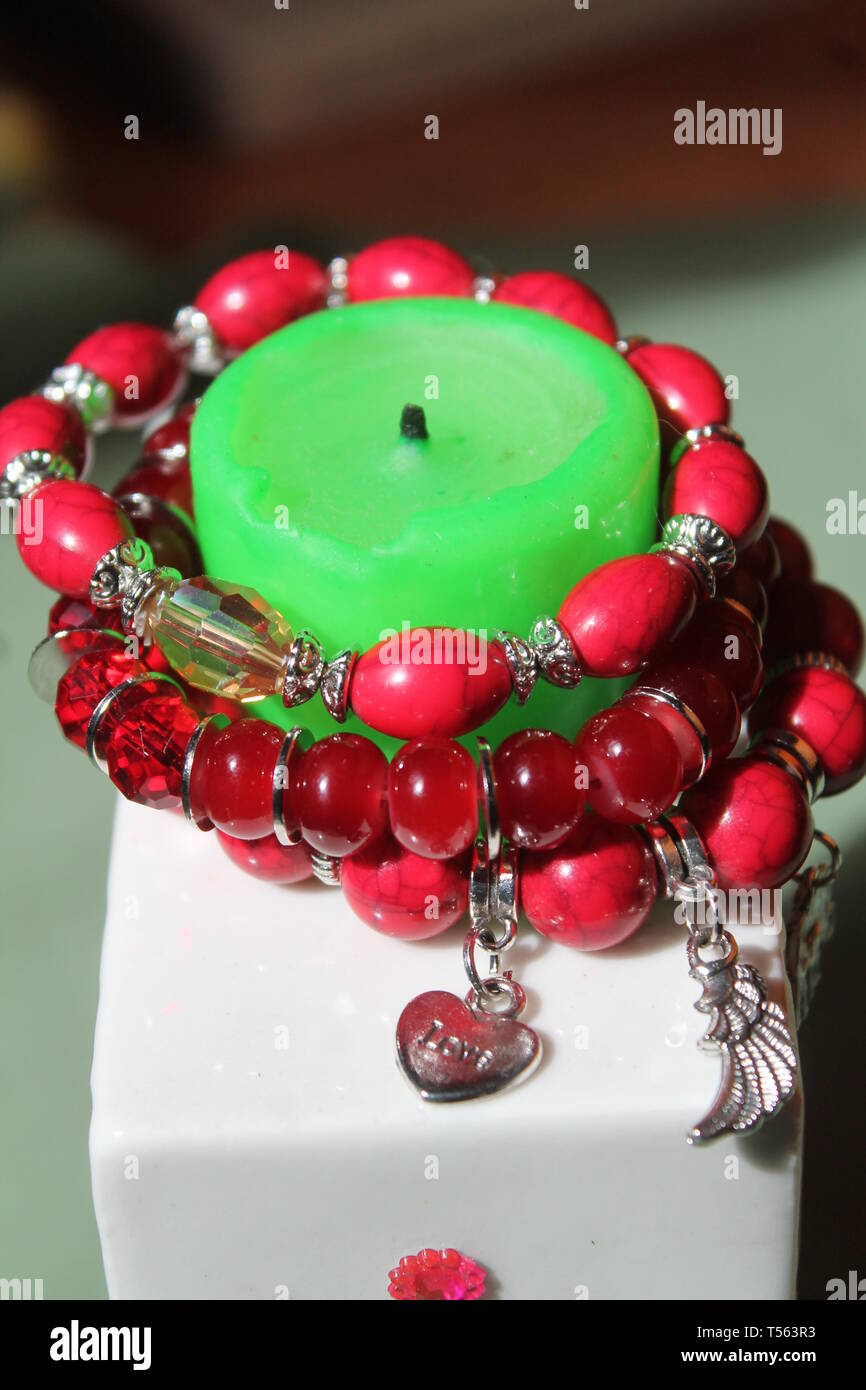 Rosso brillante bracciale con orecchini e candela rossa per lo zen e la guarigione e la meditazione Foto Stock